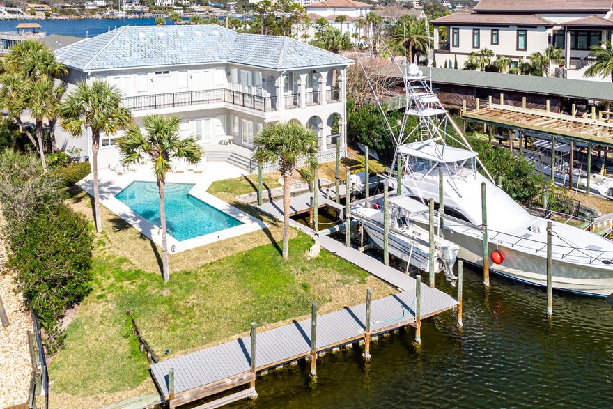 Positioned at the intersection of two canals, this boater's respite on Holiday Isle beckons the fisherman at heart with two 50' boat slips, palm-lined swimming pool, and stately facade. The improved  boating maneuverability possible at this location is a rare find on deep water.   512 Norriego is located in close proximity to the sandy shores of Destin's coveted gleaming white beaches with gated access for Holiday Isle owners and guests. This one-owner home is open, spacious, and inviting, an ideal canvas for your personal touches. It allows plenty of privacy with five bedrooms, including a bunk room with a private bath. The second-floor master suite and personal deck is situated perfectly for views of the canal.