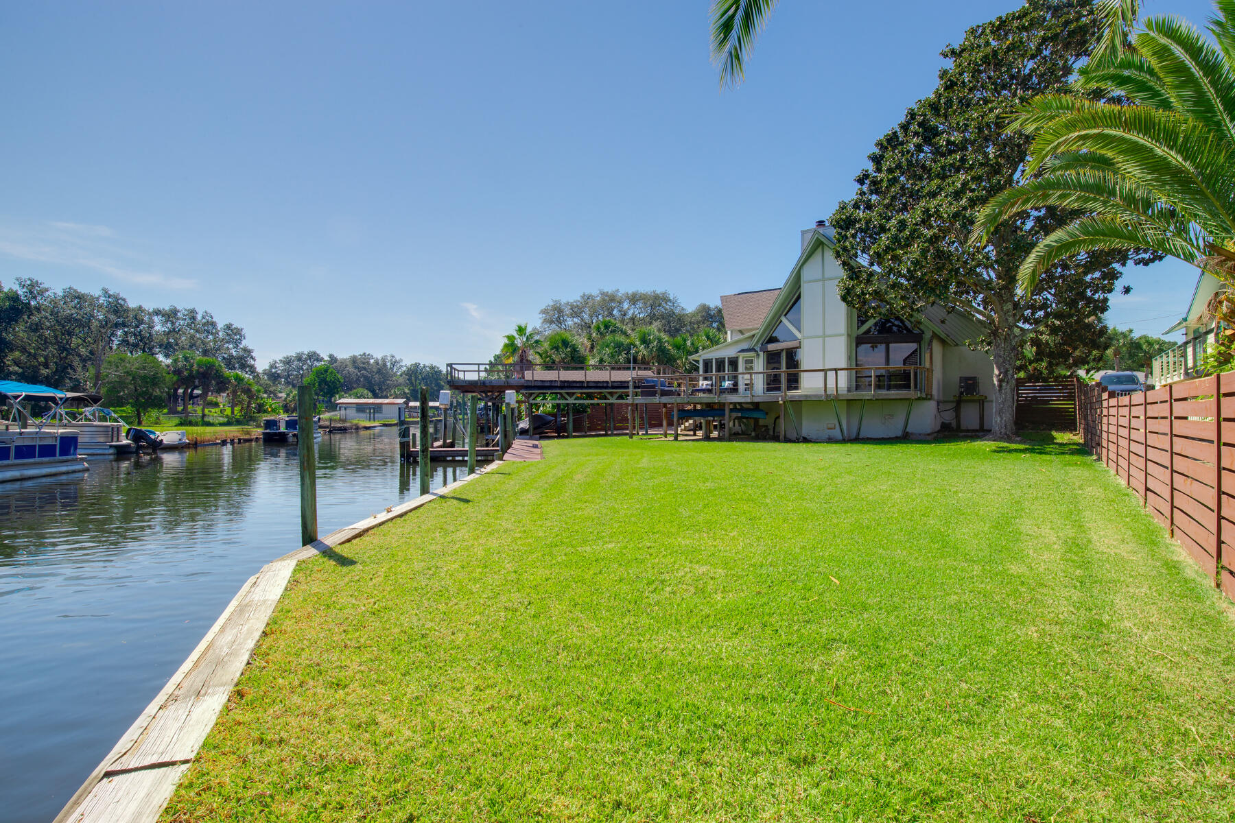 Back on the Market with a new roof and other improvements!!! This beautiful custom 3 BR 2 Bath property has over 150ft of waterfront with access to the bay. It comes with room for all your toys with two boat lifts, PWC ramp, and a tie alongside slip for a large boat/sailboat. Inside you will find an open floor plan and a large living area with floor to ceiling windows that look out toward the water.  The spacious downstairs also includes cathedral ceilings with a large fireplace and hosts two bedrooms and a full bath. A unique spiral staircase leads to the loft and master bedroom/bath upstairs. Outside are expansive decks, brick walks and driveway, and a bridge to the boathouse roof deck, as well as a walk-in basement to use as a workshop/storage space.
