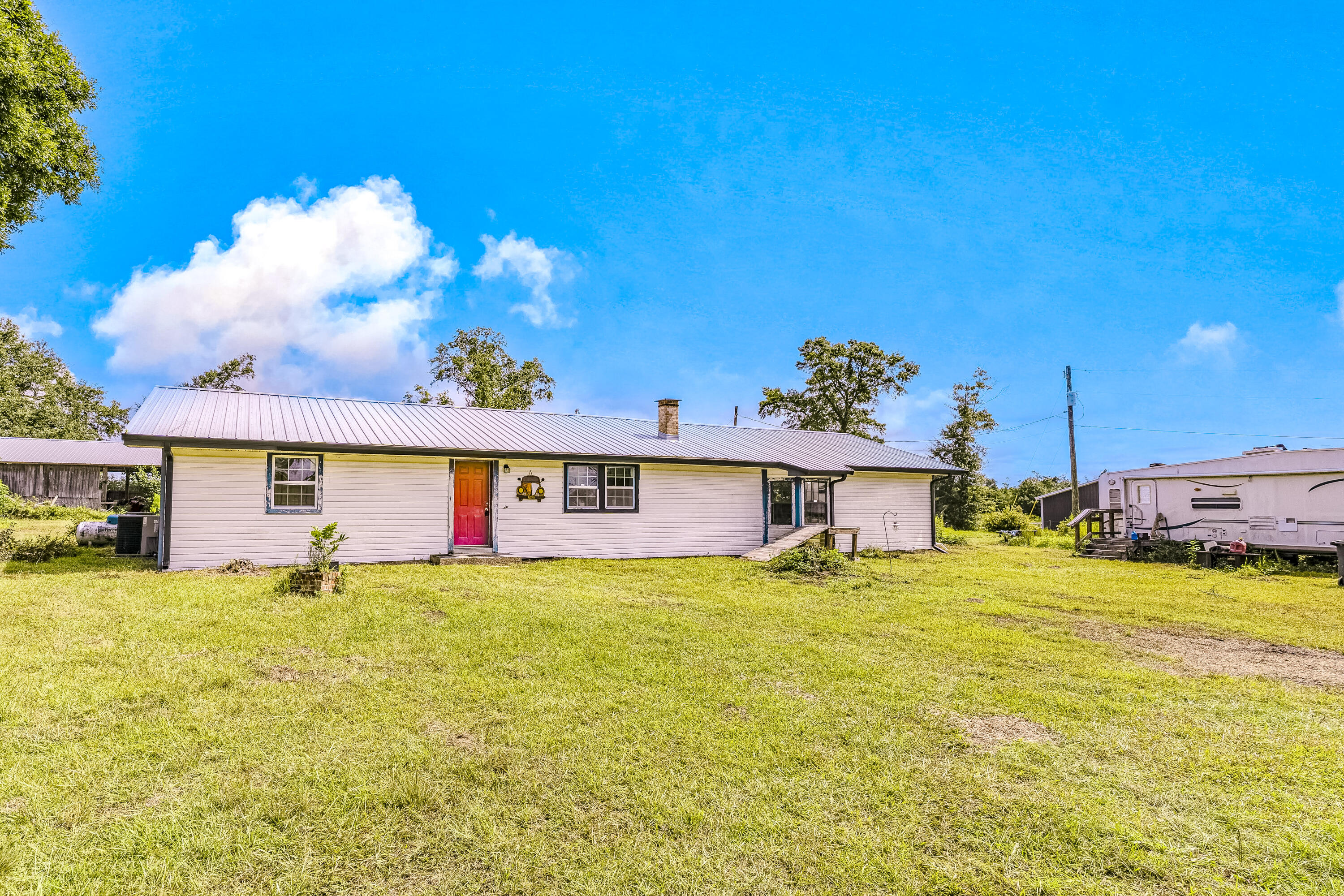 Country living at its finest - yet not too far out! This 3-bedroom, 2-bathroom home is situated on a sprawling 3.57 acre lot and features a desirable split-bedroom floor plan. Inside you'll find a space brimming with one-of-a-kind character, from the striking, custom-patterned wood plank ceilings to the rustic-chic blend of tongue and groove walls and corrugated metal in the kitchen and bath. The open-concept living area offers a welcoming atmosphere and a perfect canvas awaiting your personal touches to make it truly your own. The bedrooms are spacious and there is a separate foyer area. The expansive property is equipped with a versatile pole barn, covered porch, and an RV hookup, offering many possibilities for storage, work, or hobbies. The 2019 metal roof provides peace of mind. For recreation, you are just around the corner from Majette Park, which features a fantastic community center, nature trails, a disc golf course, and is slated for more exciting future upgrades. While you'll enjoy the serenity of your own space, you're still conveniently located just a short drive away from Panama City amenities ~ 6 miles to the nearest Publix, 12 miles to Gulf Coast Hospital, 24 miles to Northwest Florida Beaches International Airport (ECP), and only 21 miles to the iconic white sands of Panama City Beach! This is a rare chance to create your private haven with unbeatable space and potential.