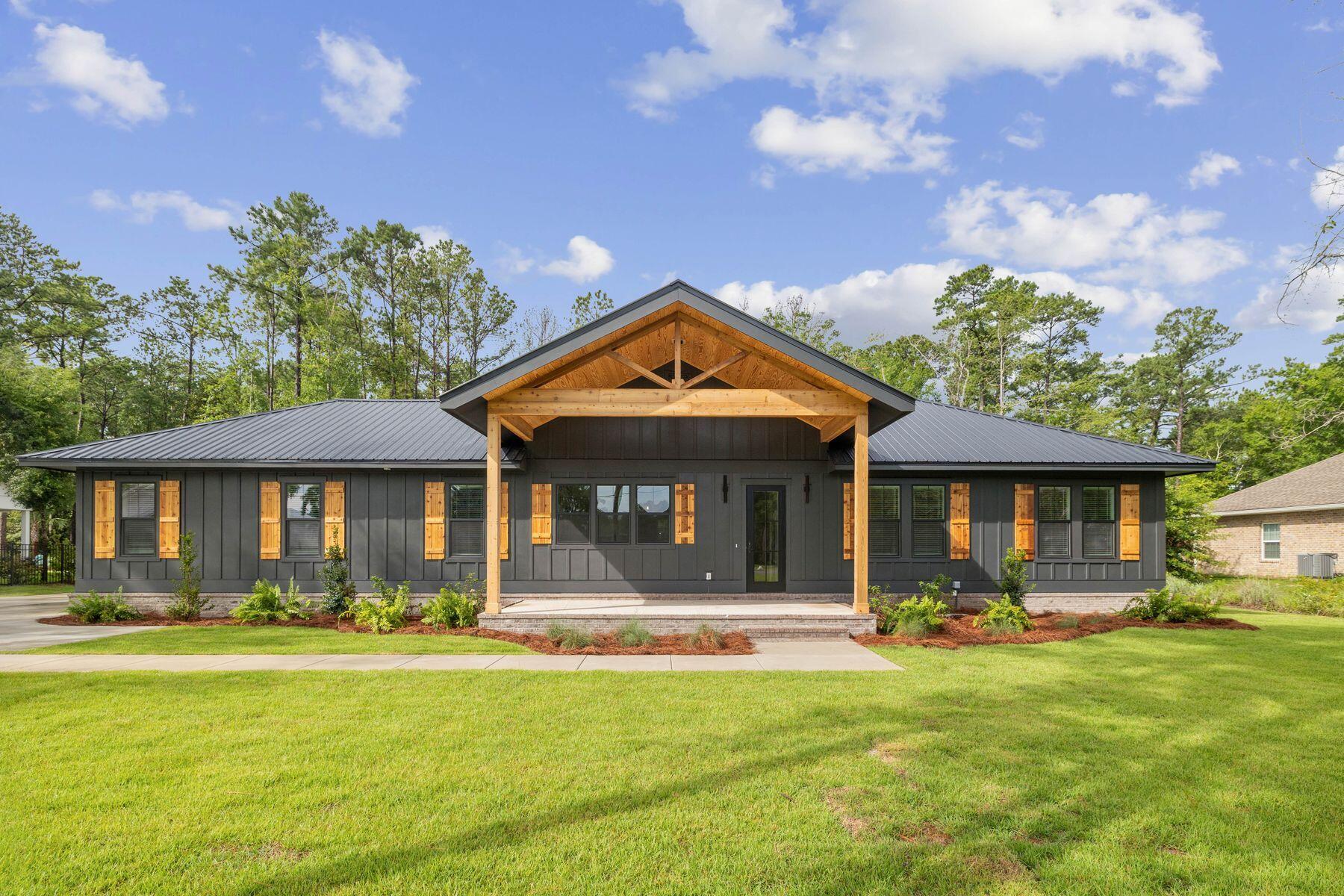 Rustic elegance meets modern luxury in this brand-new custom home just one block from Choctawhatchee Bay. Sitting on more than a half-acre with no HOA, 965 Bay Grove Road offers the privacy and freedom to live the way you want -- whether you're looking for a full-time residence, a second home near 30A, or a smart investment in a fast-growing area. The striking dark exterior, standing-seam metal roof, and natural wood accents create powerful curb appeal, while the welcoming front porch invites you to relax under soaring, exposed beams. Step inside to a wide-open floor plan filled with natural light, high ceilings, and rich engineered hardwood floors. The showpiece kitchen is anchored by a massive quartz-topped island with ample seating, flanked by shaker-style cabinetry, a dramatic marble-look backsplash, and a top-tier Thermador gas range. Pendant lighting, a hidden microwave drawer, and matte black fixtures add contrast and sophistication. Entertaining is easy with seamless flow into the spacious living area, complete with a tray ceiling wrapped in natural wood and a sleek fireplace for cozy ambiance. Large glass sliders open to a generous, covered patio overlooking the peaceful backyard, with ample room to add a pool or create your dream outdoor space. The private primary suite offers a serene retreat with a spa-like ensuite featuring a frameless glass shower, double vanity, and generous walk-in closet. The split-bedroom floor plan features three additional bedrooms, making it ideal for guests or as a home office. If you're looking for a luxury new build with thoughtful design and lasting craftsmanship in a prime location, this home delivers.