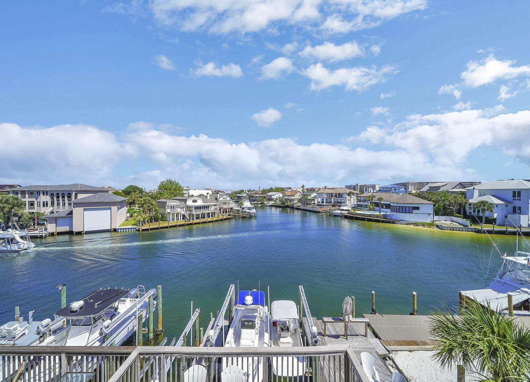 Nestled directly off the Harbor in the exclusive Holiday Isle community, this stunning canal-front townhome is a boater's paradise and a waterfront entertainer's dream. Featuring a double 12K boat lift with an option to upgrade to 16K pounds, the private boat slip accommodates vessels up to 50', making it ideal for avid boaters seeking direct and quick access to the Gulf of Mexico. The home has been thoughtfully renovated with stylish and low-maintenance LVP flooring throughout, offering both modern aesthetics and durability. Hosting is effortless with expansive waterfront decks, enclosed porches on the 1st and 2nd floors, and three scenic balconies, each offering breathtaking water views. The Master balcony even provides a delightful peek-a-boo Gulf view, perfect for savoring sunsets. For guests or multi-generational living, the separate first-floor lockout apartment ensures privacy and convenience. With two deeded and gated community beach accesses, you're only moments away from enjoying sugar-white sands and turquoise waters.  This unbeatable location blends the best of coastal living with luxurious amenities, spacious entertaining areas, and premier boating capabilities. Don't miss the opportunity to make this gem your personal retreat or lucrative investment property!  Would you like to see how it fits your lifestyle? Schedule your private tour today!