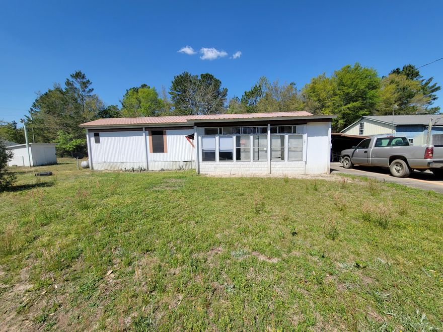 Neat and clean 2 bedrooms and 1 bath, 1977 single wide mobile home with a front add-on FL room and a back add on step-down room for a 2nd bedroom.  Home has a 'built-over metal roof,  Central air/heat, refrigerator and stove. Front porch partially glassed in and open back patio with pavers. Property has a 2 car-carport (needs work), paver back patio and 2 yard buildings.  Septic in front yard to the left. Just off Hwy 90 West. Great location for workers in DeFuniak Springs, Ft. Walton, Crestview and Destin areas.  It is appx. 5 miles to the I-10 exit at Mossy Head.  Ask about the adjoining  80x125' lot for sale also.  Seller holding it off the market till mobile sells.  CASH BUYERS ONLY DUE TO THE AGE OF THE HOME.  Being sold 'AS IS'