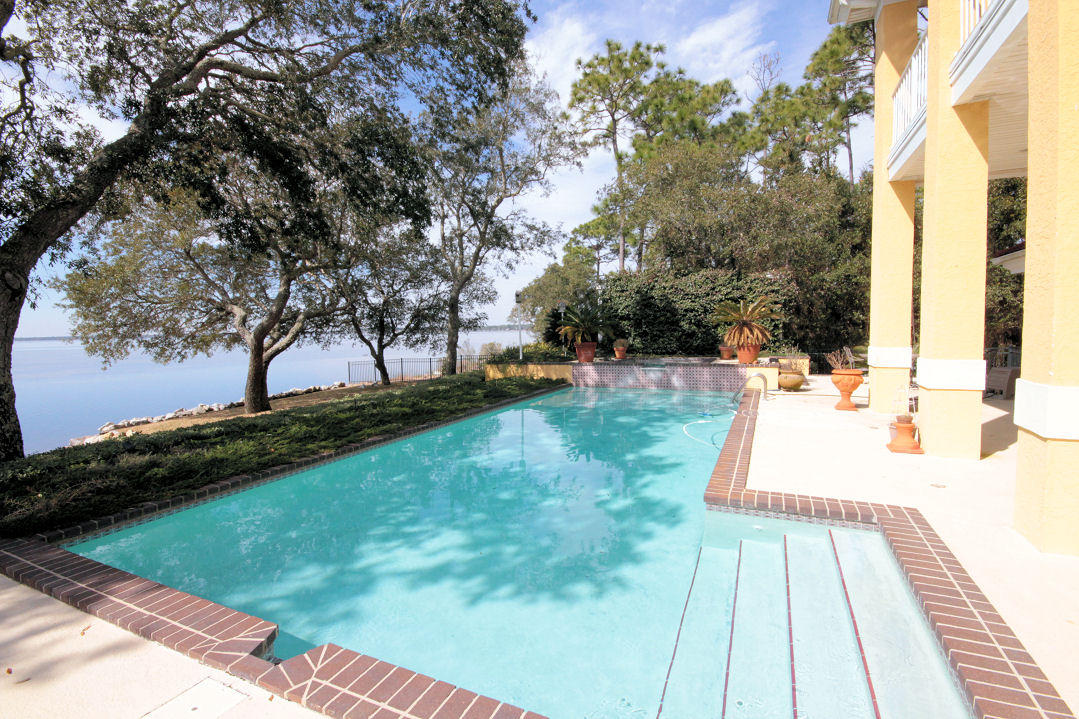 UNBELIEVABLE price reduction on this exquisite, custom built waterfront home in the gated Bluewater Bay community of Windward. This amazing home with 99' on Choctawhatchee Bay is located on a western facing lot offering panoramic sunset views! This property was carefully designed to offer the very best of waterfront living from the covered outdoor entertaining area along the back of the house to the raised pool and hot tub and out onto the grassy yard leading to the dock and boathouse over the bay. Along the back of the house is a covered patio as well as an open patio surrounding the pool. This is the perfect place for outdoor entertaining all year around. The heated pool is accented by imported mosaic tile and the raised hot tub features a cascading waterfall splashing into the pool.