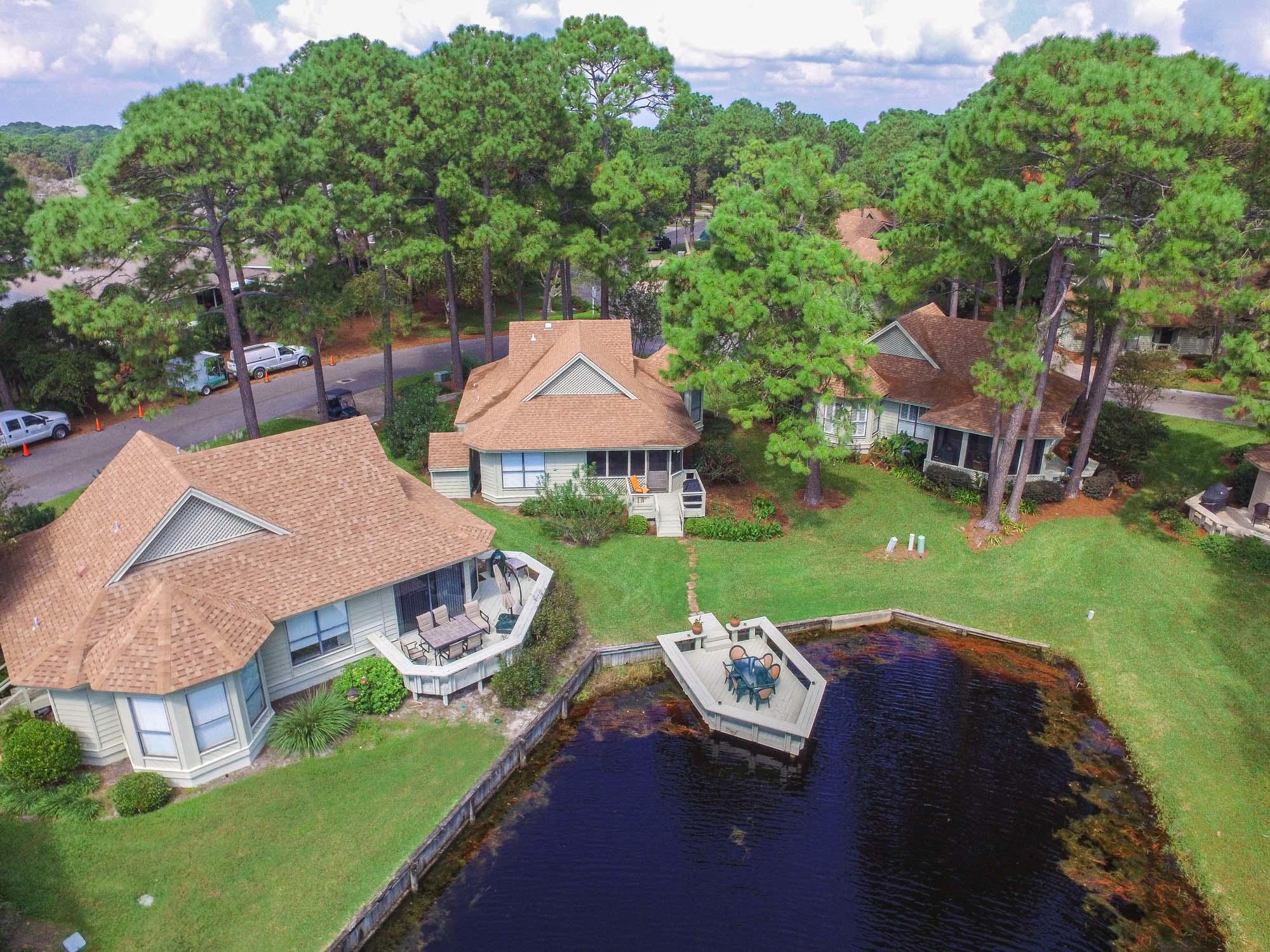 Situated among majestic pines and lush landscaping on a quiet pond sits a haven from the everyday. This lakefront cottage with dock offers an abundance of space for family and friends to relax, reconnect, and unwind in comfort at the beach. Natural light and tranquil, panoramic lake views flow throughout the cottage. Enjoy the shade and lusciously landscaped neighborhood that's close to the action but quiet enough to recharge and relax. This charming single story home offers a little bit of everything including a spacious screened patio and dock for additional entertaining and relaxing. There's a large storage shed useful for your beach chairs, toys, and bikes. Sold furnished (list of exclusions) including golf cart and two bikes.