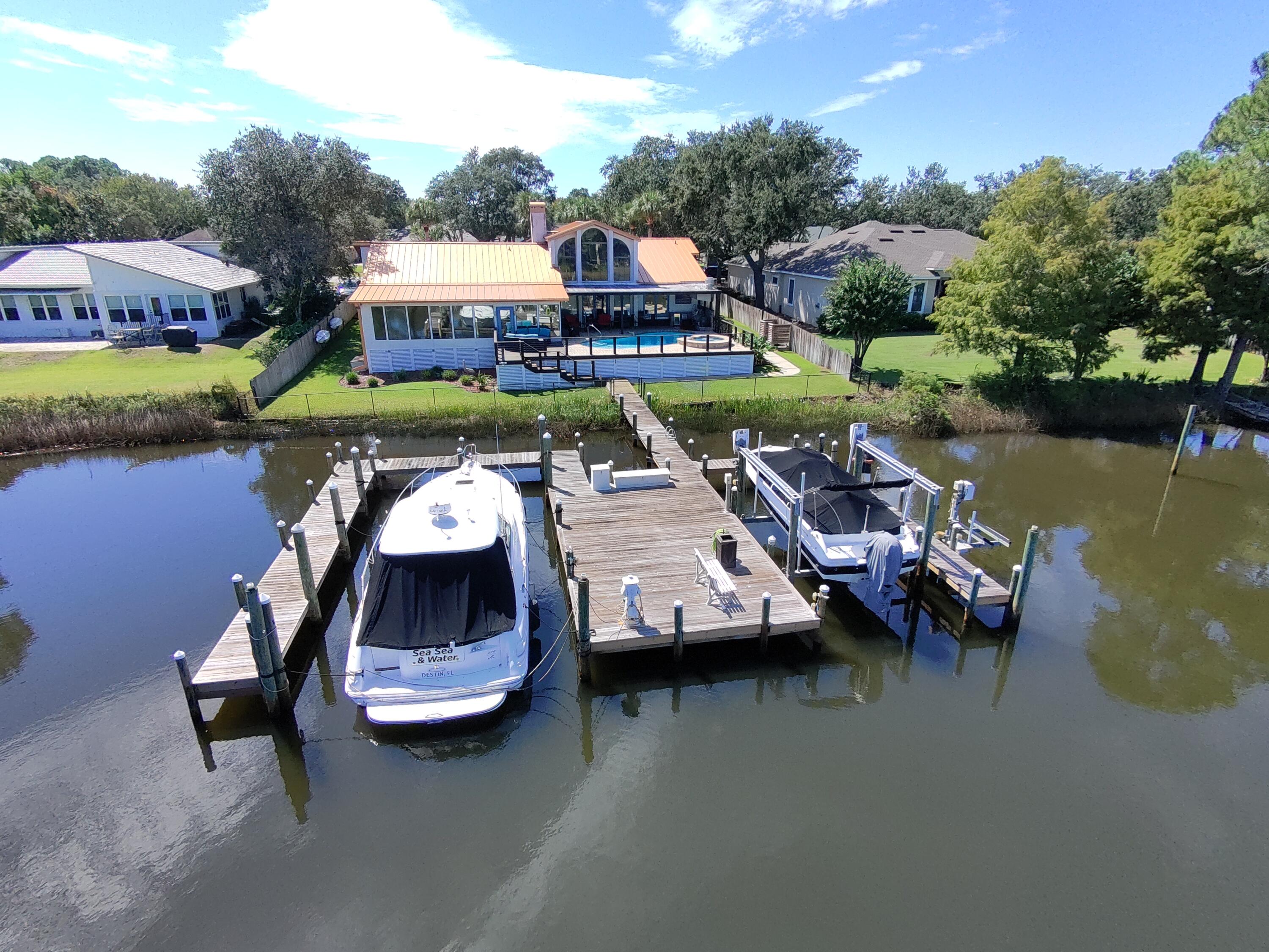 This exceptional home offers deep-water moorage and 100 feet of waterfront on Indian Bayou. Enter to a great room with a stunning 28-foot cathedral ceiling and large windows showcasing beautiful water views.The gourmet kitchen has been fully renovated and features two islands--one with a copper apron sink--along with granite countertops and custom cabinetry. High-end appliances include a Dacor under-counter microwave, Wolf gas stove, double oven, warming drawer, and a hidden fridge with freezer drawers. The open layout connects to a formal dining area and an office with built-ins.Relax in the family room with water views, a gas fireplace, and a custom media center. The fully screened lanai features a resurfaced heated pool and hot tub, perfect for year-round enjoyment. The pool is equ equipped with multicolor LED lights, creating a stunning atmosphere for evening gatherings. Adjacent to the pool is a summer kitchen designed for entertaining, featuring a mini-fridge and a premium grill, making it easy to host friends and family.
The master suite offers water views, a sitting room, and a luxurious bath with double vanities, a large shower, a Jacuzzi tub, and two walk-in closets. Two additional bedrooms and baths are located on the opposite end of the home.
The boat dock has two large slips and can accommodate a 50' x 20' boat with a lift and a jet ski lift. Additional features include a new commercial metal roof, water softener, security system, climate-controlled garage, weatherproof back deck, fully fenced yard, generator, and both gas and electric water heaters. This home is perfectly situated in central Destin, offering convenience and luxury. Don't miss out!