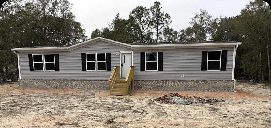 Discover this stunning brand-new manufactured home and enjoy being its first owner! Exterior highlights include upgraded brick skirting for added durability and curb appeal, plus a spacious back deck ideal for outdoor entertaining. Located on approximately 0.38, this home offers a spacious open-concept layout with split bedrooms for comfort and privacy.The main living area showcases a stylish framed accent wall, creating a warm and modern feel. The kitchen features a deep stainless-steel sink, smooth-top stove, dishwasher, and a full wall of cabinetry surrounding the refrigerator for excellent storage. A large center island provides extra prep space and seating. This home offers 3 bedrooms, 2 bathrooms, and dining space to suit your needs. The primary suite includes a walk-in closet, double vanity, soaking tub and walk-in shower. 
Conveniently located just minutes from historic downtown DeFuniak Springs.
