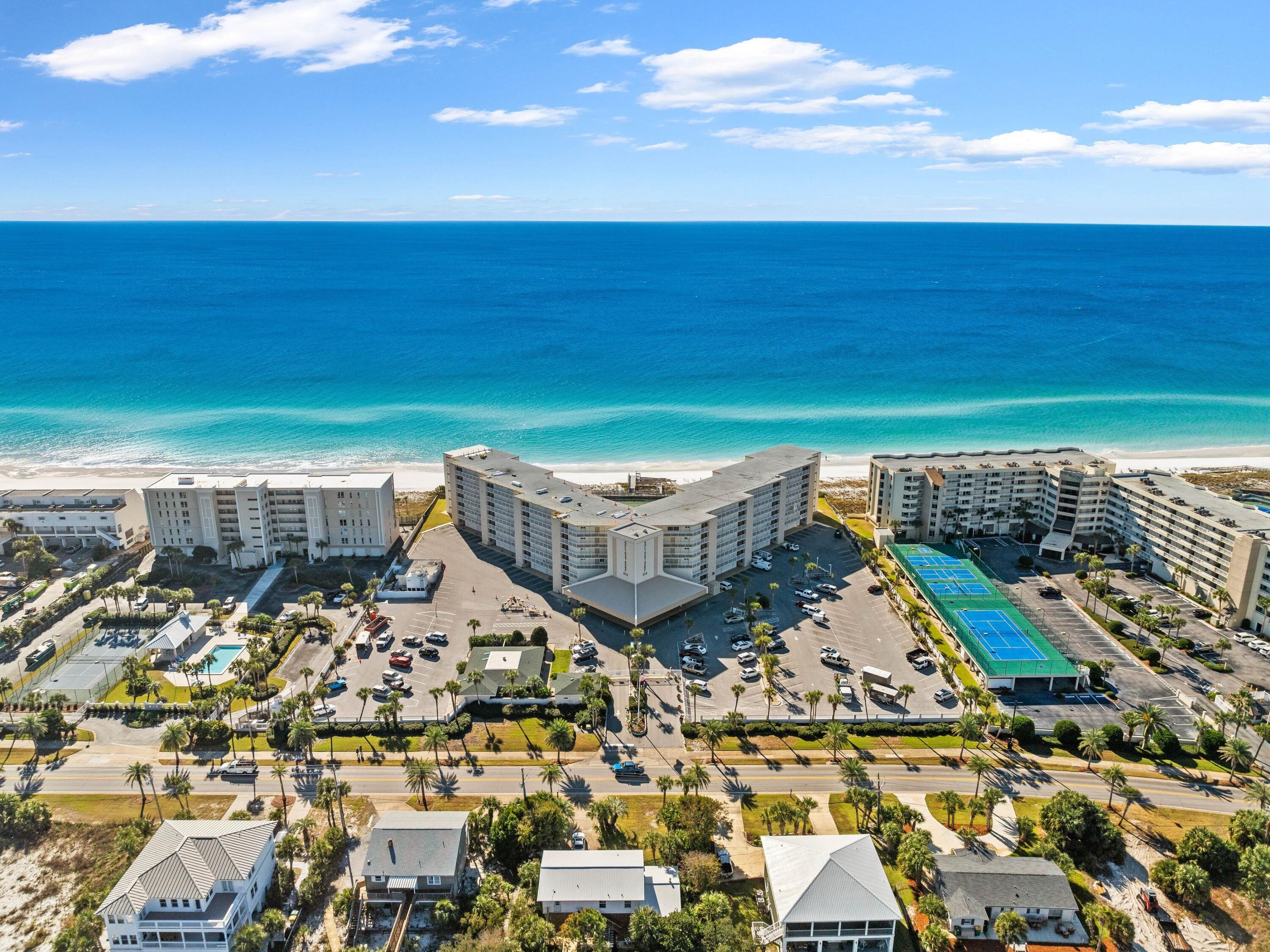 Experience coastal living at its finest in this newly renovated ground-floor condo, ideally situated within the highly desirable Holiday Surf and Racquet Club in the heart of Destin.  This charming and fully furnished one-bedroom, one-bathroom unit boasts an inviting and contemporary aesthetic, featuring low maintenance, wood-looking tile flooring that extends seamlessly throughout. The kitchen is a true highlight, showcasing shaker-style cabinets, a stylish tile backsplash, stainless steel appliances, and stunning quartz countertops that effortlessly combine functionality with modern design.  Step into the living room, where you'll find a tongue-in-cheek ceiling that enhances the airy feel of the space, perfect for entertaining or unwinding after a day at the beach. The outdoor patio is a private oasis, equipped with comfortable rocking chairs that invite you to relax and soak in the ocean breeze. With convenient walkout access to the pool, you can enjoy a refreshing dip anytime or take a short stroll to the beautiful sandy shores.

The Holiday Surf and Racquet Club is renowned for its exceptional amenities, making it a coveted destination for relaxation and recreation. An impressive boardwalk leads to beach access, where you can revel in the sun and surf. The complex features a heated pool for year-round enjoyment, sauna rooms for a soothing retreat, tennis and pickleball courts for sports enthusiasts, and shuffleboard for casual fun. Stay active in the well-equipped fitness room or unwind in the game room complete with a pool table. For added convenience, a laundry facility is available on-site, and the ample green spaces provide plenty of room for outdoor activities and play.