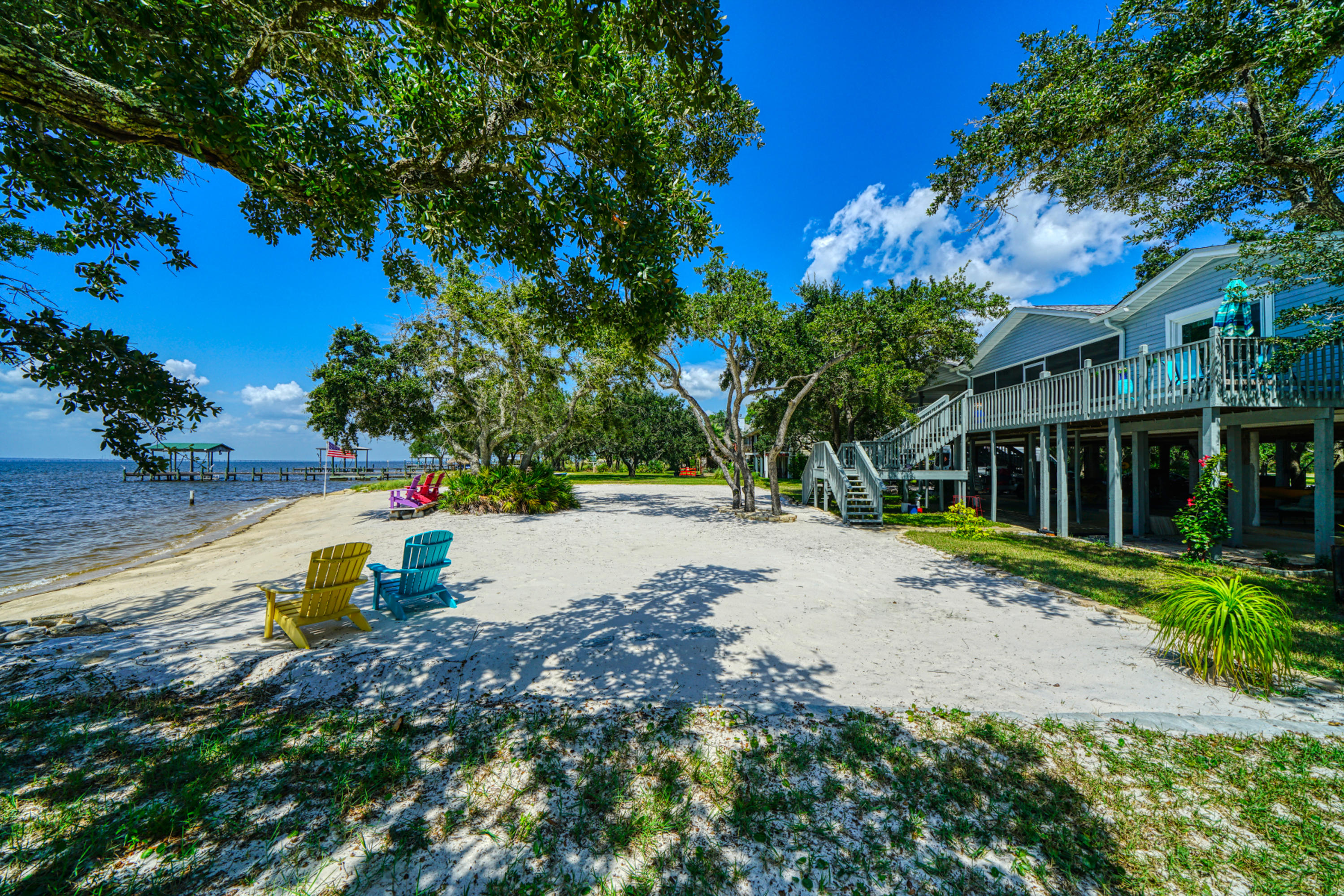 Bayfront living at its finest in this 3 bed / 2 bath 1512 sq/ft pole house that has 126 feet frontage on Escambia Bay. The expansive deck overlooks a sandy beach with plenty of room for volleyball. Mature shade trees are all over the 1.2 acre lot. The deck has been extended & a screened in porch added. Bay facing windows have recently been upgraded to hurricane impact, new flooring in the living room and all bedrooms, upgraded counter tops in kitchen and bathrooms. Access from staircase in covered parking or from 1 of 2 outside staircases. There is plenty or room for all your toys on the concrete slab under the house, and the lot is wide enough to park an RV on the north side of the house. 20 minutes to the beach or PNS airport. Free Sunsets nightly!