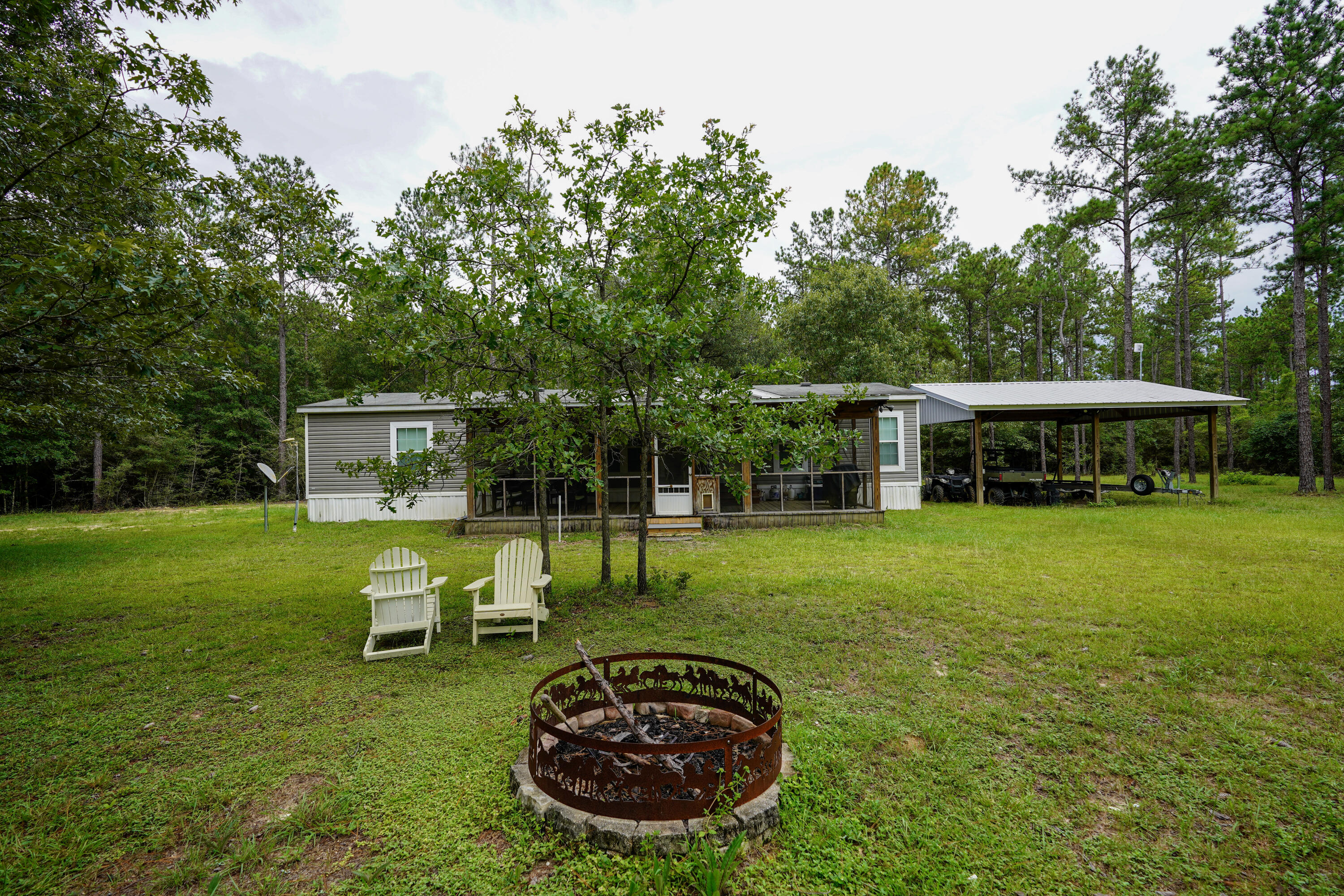 Turn Key 32 acre retreat in Walton Plantation. High and dry with absolutely no wetlands. This rare offering includes two parcels and features Oak, Magnolia, and Dogwood trees throughout. Property lines are cleared, and multiple hunting areas are ready to go. A well-maintained 3BR/2BA manufactured home offers ceiling vents, a screened porch, and comfortable living space. Improvements include two pole barns, power, Septic, and a private well. Enjoy easy access with two gated entrances, one at each end of the property. Perfect for a private homestead, hunting camp, or long-term investment. One of the finest tracts in Walton Plantation!