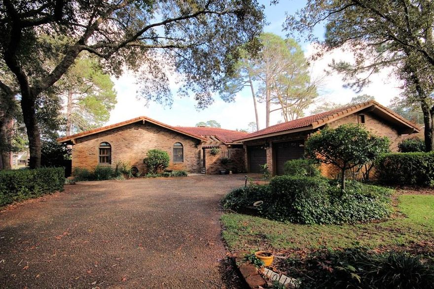 Located on the Lake golfcourse of Bluewater Bay, this home with a fairway view pool is sure to impress you with its charm and uniqueness. In the back of the home is a 2,000sf brick paver patio surrounding a sparkling pool that is kept nice and cool by retractable awnings along the full length of the Florida room. The pool is surrounded by a brick and wrought iron fence and on the other side is a good sized yard separating you from the golf course. The pavered driveway leads to a side loading garage and private courtyard entrance. Upon entering this home through the wide foyer, you will immediately notice the unique arches that define the living areas of the home and the custom hexagonal tile floors throughout. To the right is a large kitchen and breakfast area accented by a built in wall