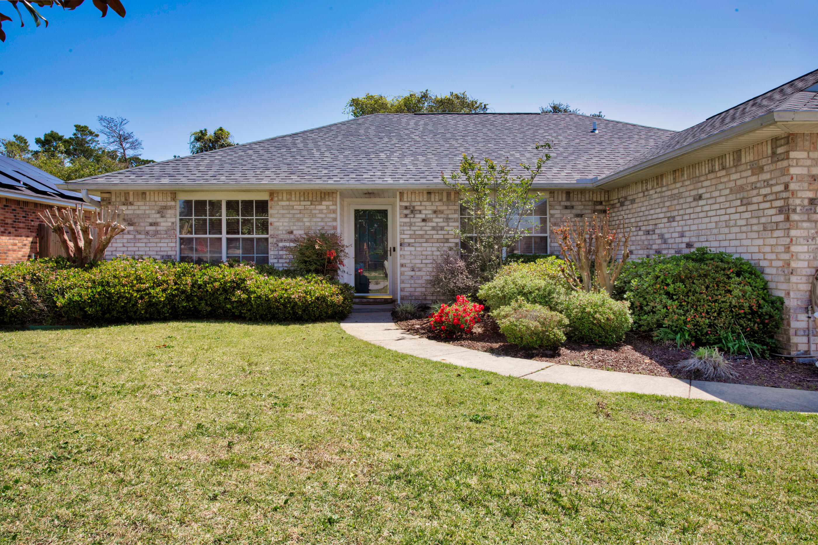 Imagine enjoying the natural beauty of Navarre with deeded neighborhood access to the tranquil waters of the Santa Rosa Sound including a community pier, perfect for fishing or watching unforgettable sunsets.  This delightful and impeccably maintained 3-bedroom, 2-bathroom home awaits within the charming Sandy Beach Estates. Sunlight dances through the main living areas, enhanced by the elegant flow of hardwood and tile flooring. The kitchen showcases sleek Corian countertops and generous cabinet space, with all appliances ready for your use. Gather with ease in the dining area, featuring a convenient bar and wine refrigerator.