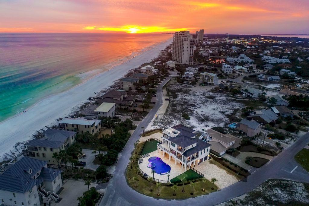 Discover this sleek coastal compound perfectly situated on a sizable 1/3 acre lot directly adjacent to the pristine white sand beaches of the Gulf of Mexico capturing 180 degree gulf views from each of the three finished levels as well as the fourth story rooftop deck. This masterful property is comprised of 5,990 heated and cooled square footage paired with unparalleled indoor and outdoor entertaining space offering several expansive covered porches as well as notable amenities including a private in-home theatre with commercial style outfitting as well as a massive private pool area totaling 1,100 square feet complete with dual fire features, water features and an adjoining spa with ample capacity.