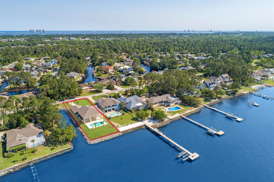 This regal waterfront estate resides on Pensacola Bay and offers a gunite pool with a 3 car garage and an open spacious living area. Embrace the ample natural light that floods into this gorgeous home with stunning water views from the entire living area. Ideal for entertaining, this home offers a sizable kitchen with a  formal sitting/entertaining area, formal dining room and covered lanai (47'x14'). Enjoy the resident dolphins that frequent the area daily and relax and enjoy epic sunsets from your backyard oasis. The kitchen comes equipped with custom cabinetry with pull out drawers, granite countertops, a plethora of cabinet storage and counter top space, double wall oven, 5 burner electric cooktop, prep sink, built-in desk and walk-in pantry. The primary suite has a separate entrance t