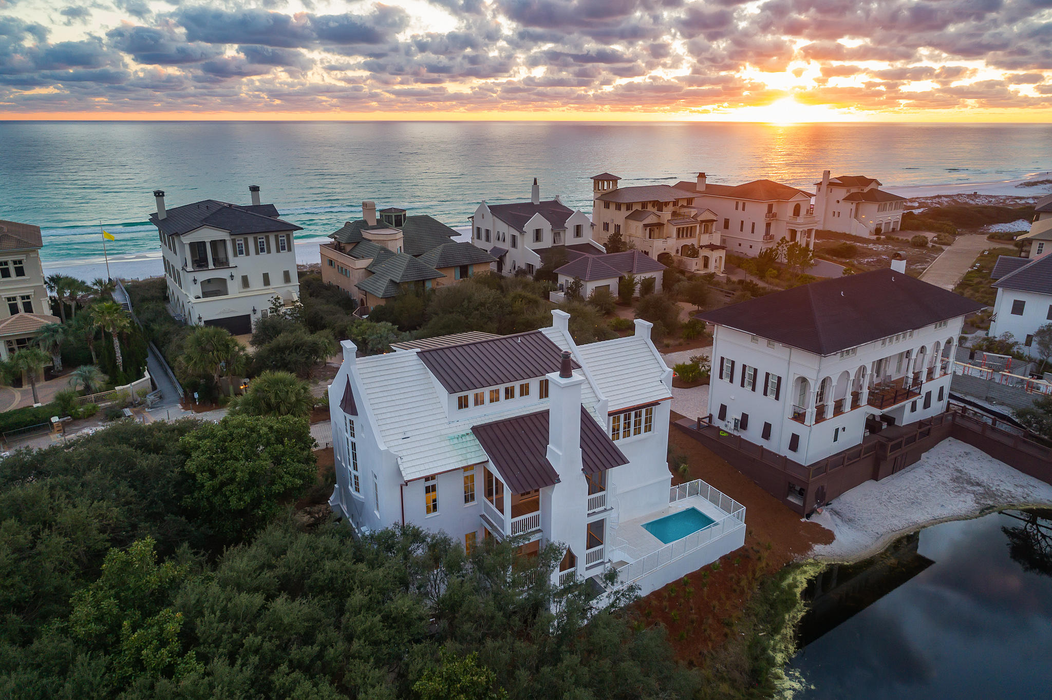 Tucked behind the private gates of Stallworth Preserve resides this like-new residence constructed by renowned builder Matt Fuller. The masterfully planned non-rental community offers the epitome of coastal living while taking full advantage of the stunning Gulf and lake views. The brass inlay found in the foyer's herringbone floor sets the tone for the captivating architectural components found throughout.Encompassing over 4,200 square feet, the reverse floor plan is interconnected by a staircase adorned with venetian plaster along with a three-stop elevator. The positioning of the three guest suites and bunk room on the first level makes way for the spacious living and kitchen areas on the second floor surrounded by 360 degree views and custom pecky cypress accents.