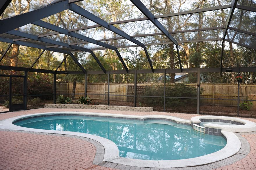 Beautiful four bedroom home with metal roof and a beautiful lanai covered heated salt water pool in Bluewater Bay Area!  Open floor plan with tiled floors, formal dining room, large living room with vaulted ceilings and wood burning fireplace. The beautiful kitchen features a gas stove, tile backsplash, quartz counters, stainless appliances & a Butcher Block Island with pot rack. The large master bedroom has decorative tile floors and access to beautiful sunroom. The heated and cooled sunroom leads to the lanai covered saltwater pool & spa with herringbone pattern paved deck. The driveway has plenty of parking in addition to the two car garage and the large backyard offers an outside storage shed behind the lanai. There are 2 water heaters (electric 2019 and gas 2019) and surround