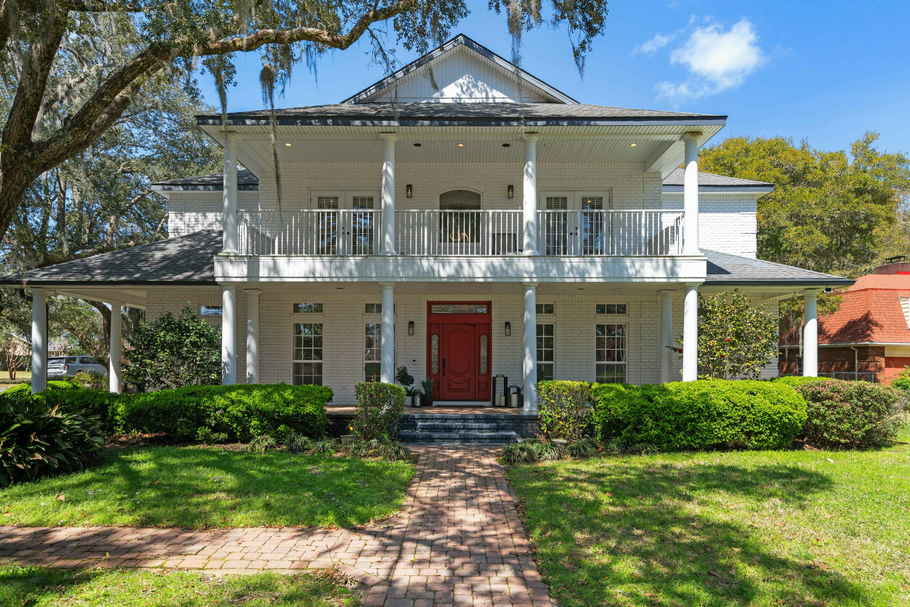 On a corner lot with over 4,500 sq. ft., this 6 bedroom Colonial-style home with a 3 car garage blends charm and modern updates in a luxurious setting. Inside, the spacious living areas are enhanced by a grand marble fireplace and vaulted ceilings, creating a warm and inviting atmosphere. The chefs kitchen has sleek countertops, high-end appliances, and a breakfast nook, making it the perfect space for entertaining. Step outside to enjoy multiple wrap-around porches that offer stunning views of the lush landscaping and provide plenty of space for relaxing, dining, or enjoying the outdoors in comfort. The private screened-in pool and spa are seamlessly connected by the lanai, allowing the doors to all open up and creating a inside/outside space for year-round enjoyment.