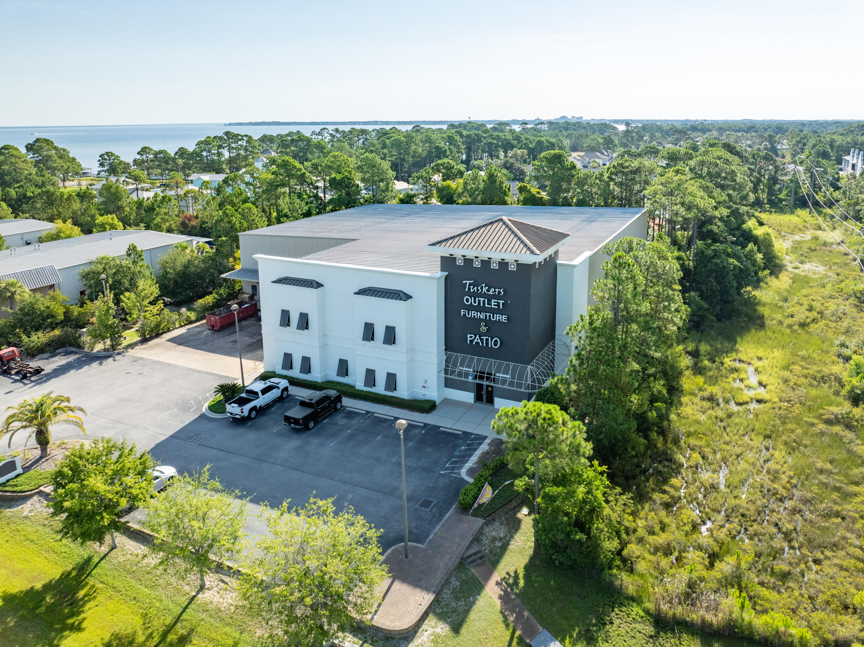 This subject listing offers the Tusker's warehouse, excluding the freestanding retail building fronting Highway 98 (freestanding retail building also available via MLS 978842). This rare assemblage of prime retail, showroom, and warehouse does not currently exist in the local market, which is adjacent to the synergistic retail nucleus of Silver Sands Premium Outlets and centralized to all the local mixed-use districts, successfully drawing population from all local peripheral sub-markets, including but not limited to Destin and Scenic 30A of Santa Rosa Beach, Florida. Fronting Highway 98 in Miramar Beach, nearly 50,000 vehicles pass by its 196 fronting feet daily, which ingress and egress lures the traffic into the retail facilities through the convenience of... the traffic light at N. Geronimo Street and Highway 98. The current owner has committed significant capital to renovate both buildings, which even includes approximately $300,000 for new escalators to service the second floor of the main showroom. Parcel 1 contains a two-story building, oriented on ??1.18 acres, hosting prime retail and showroom space, as well as private offices, collectively measuring ??26,893 conditioned square feet. There is a 3rd floor that accommodates a spectacular executive office, accessible via a private & secured "floating" staircase. The structural integrity of the building is phenomenal, and the finishes throughout are exceptional. Parcel 2 contains a warehouse, office, and showroom, situated on ??2 acres, and constructed in 2004, measuring ??11,282 SF on two floors. The warehouse contains a broad loading dock area and massive rack system with a lift and guide rails. Both buildings project an architecturally magnificent image. This opportunity is irreplaceable locally, as land development code would neither accommodate this massive yield, nor would a developer endeavor upon such a project, as the inflationary costs of this era, coupled with land costs, (even if such prime vacant land at a traffic light were available, which is non-existent), would likely much exceed $20,000,000+. The current business is operating a record-breaking levels, year over year; thus the attributable value to this extremely prime site and assemblage is likely understated. All showings are by appointment only and require a minimum of 48+ hours advanced notice. The listing broker must accompany all showings. Financial credentials are required prior to confirmation of any showings. Please do not approach any onsite staff.