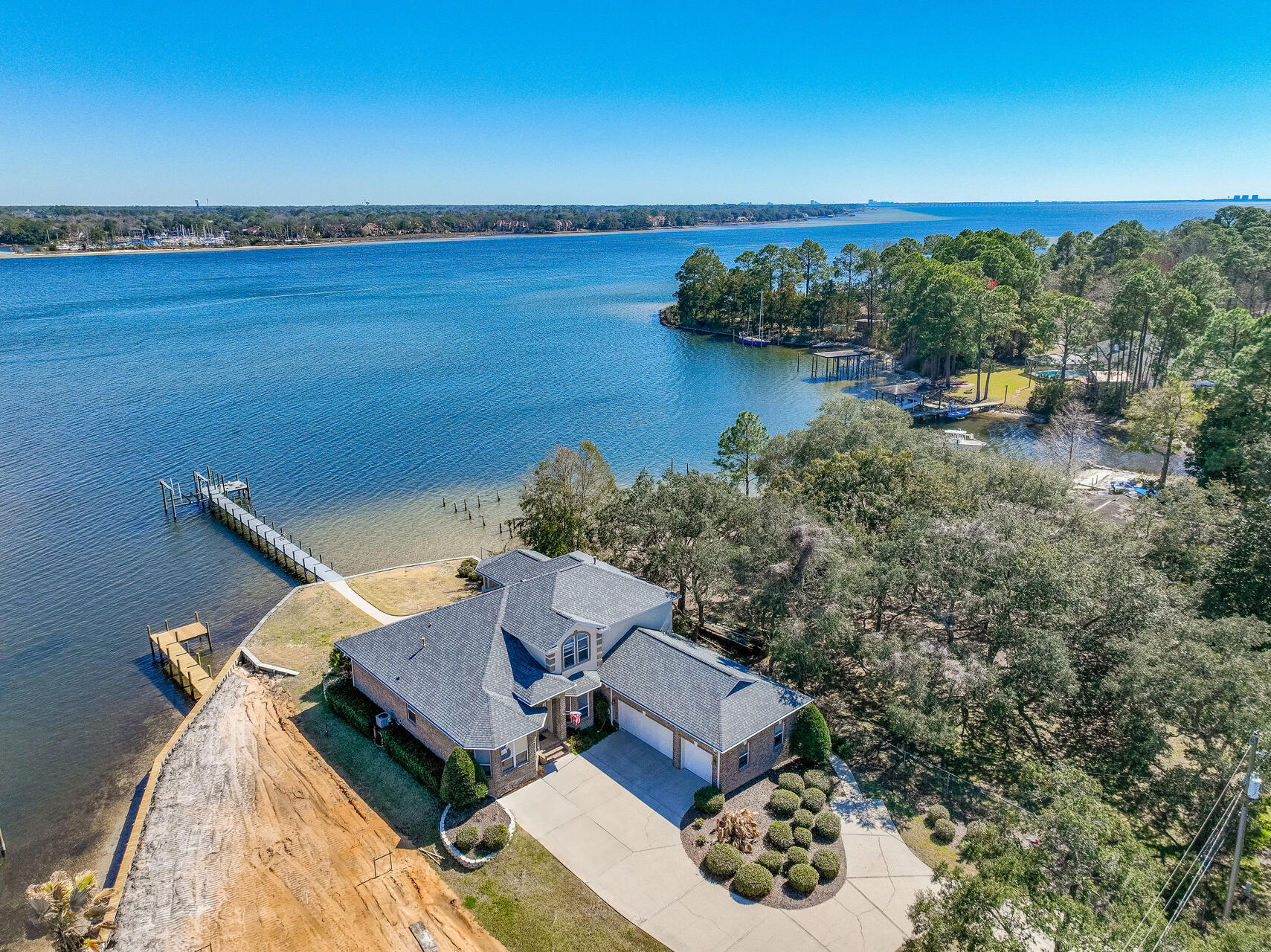 Welcome to your waterfront dreamhouse located on a deep water lot on Rocky Bayou in South Niceville!! This home on .36 acres was custom built for Gary Miller Homes in 2004. It features the Master bedroom, a 2nd bedroom, 2 full baths and an office on the main level and two additional bedrooms, another full bath and a loft leading to an upstairs balcony on the 2nd level. The views from practically every room in the house are spectacular and there is plenty of room in the back yard for a pool. The boater in the family will enjoy the deep water boatlift at the end of the dock and the quick trip to Crab Island and the Destin Pass! When you drive up to this home you will appreciate the circular driveway for extra parking and the 3-car garage as well. When you enter this home through the wide foyer, you will find the office with built ins on the left and the formal dining room on the right. Directly in front of you is the family room with unparalleled views of Rocky Bayou. The kitchen and breakfast nook are open to the family room and there is a convenient door leading from the nook to the covered porch in the back of the home. The master bedroom suite with a luxurious bath and a large closet are to the left of the family room and offer amazing bayou views as well as another door leading to the covered porch. The 2nd bedroom and another full bath are on the right of the home between the kitchen and garage. Upstairs you will find a spacious loft featuring a mini-refrigerator and sink that has sliding glass doors leading to a covered balcony with panoramic views of Rocky Bayou and the Bay beyond. There are also two additional bedrooms and another full bath upstairs making this area perfect for multi-generational living! The living areas in the house extend to the covered back porch with an outdoor kitchen, perfect for outdoor entertaining. There is an open patio area off of the porch with a raised deck making this the perfect place for a hot tub! You will enjoy evening strolls along the private sidewalk leading to the private dock with a large platform at the end. Practical notes include: Roof (June 2024), tankless water heater and 2 HVAC's (2014 & 1016). Don't let your waterfront dreams pass you by, make them a reality!!