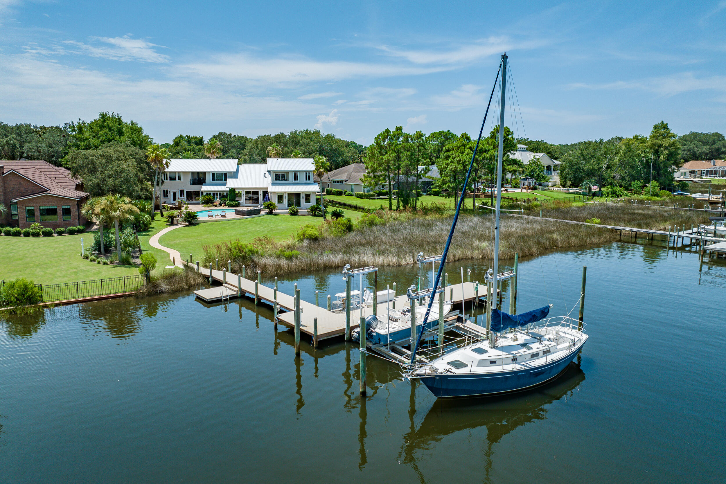 Fabulous Deepwater, Bayou front Estate with incredible Bay & Bayou views with 150' of waterfront.  Home boasts of 5509 SF with multiple living areas, 5 spacious ensuite bedrooms, (4 bedrooms with bay views) 2+ offices, gym area, 2 laundries, 2 Mother-in-law Suites., 2 Bay balconies, 3 kitchens & more. The Dock has been upgraded with Trex decking & can accommodate multiple boats and other watercraft.  Large Dock includes a 30,000-pound, 4 motor boatlift. Outdoor gas kitchen with wood burning fireplace compliment the pool and wonderful views. New metal roof, exterior paint and exterior lighting, ALL in 2023. The Gourmet kitchen has a beautiful granite island, stainless appliances, 6 burner Wolf Gas Range, high-end cabinetry and eat in kitchen. Home has 3 HVAC Systems and a gas Generator. Home has partial Hurricane Shutters, 2 new instant water heaters, new sod, and new pool pump.  It also conveys with a central vacuum system, gas fireplace in Living room and Primary, and interior finished attic.  Recent upgrades have been completed to primary bath and mother-in-law kitchen and bath.  Master bath has 3 vanities.  The ceiling heights in the living room are up to 17', the east wing mother-in-las ceiling heights are 12' and west wing mother-in-law suite has up to 12' ceiling heights.    The long driveway can accommodate 8+ vehicles for your family and guests.  The garage is oversized with shelving installed.   Olympus Home insurance policy is $7854.00 per year.  Frontline Flood Policy is $827 per year.  Flood Zone is AE.