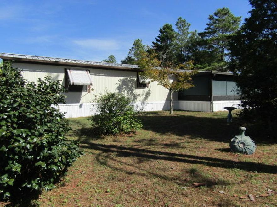 Well maintained 2 bedroom, 2 full bath mobile home with over an acre of land. There is an enclosed bonus room addition on the back of the home with a window AC and an enclosed front porch/Florida room. In the back yard is an awesome Pole Barn on a slab with electricity, water and septic, that was built to park a motorhome. The Pole Barn also has a kitchen, a bathroom, a workshop and tons of storage overhead. Beautiful azaleas and trees accent the property making it a great outdoor area for a cookout or fish fry with family and friends with a chain link fence around the entire property to keep the kids safe. In this price point and with all it has to offer, it won't last long.