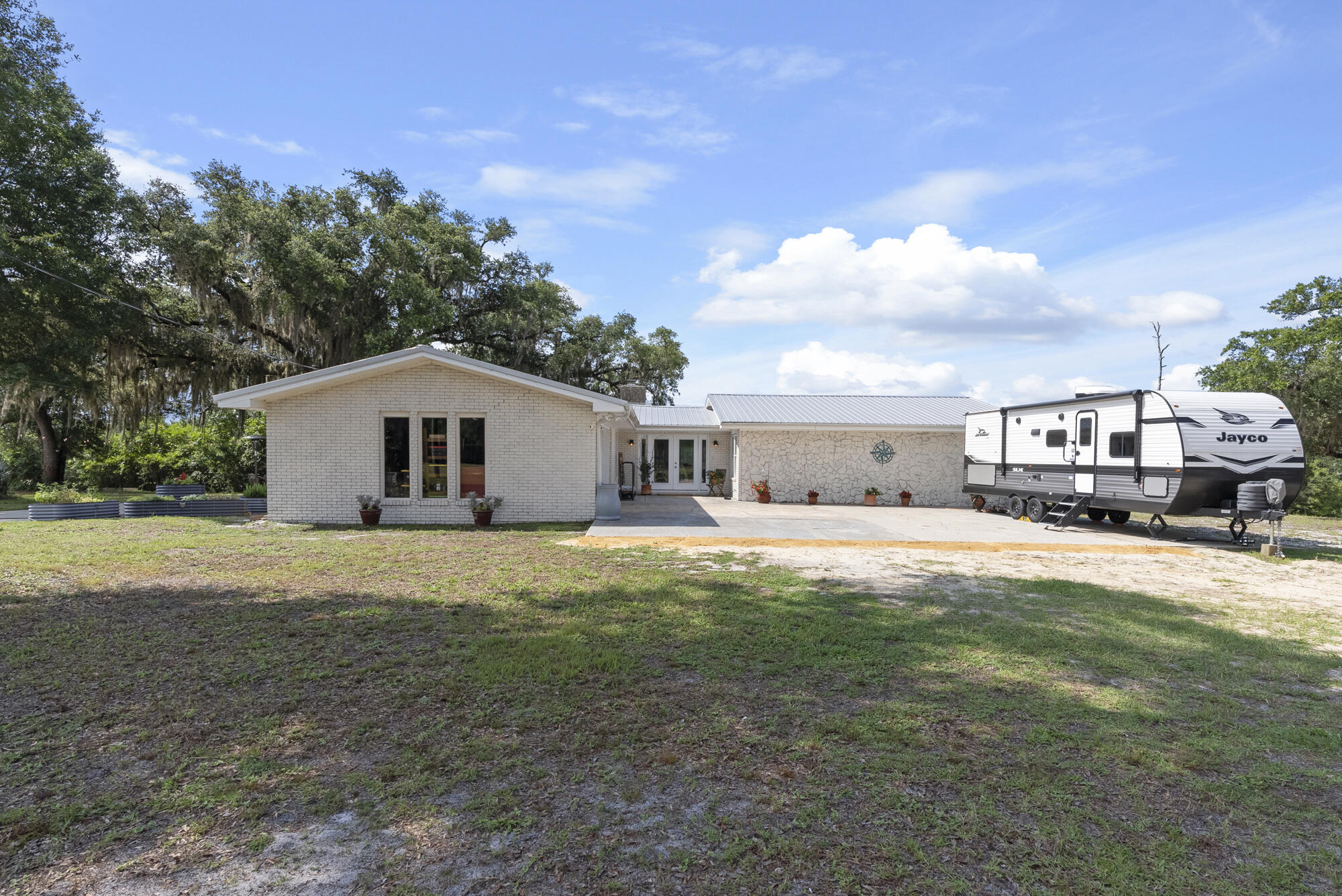 PRICED BELOW APPRAISED VALUE Welcome to your own slice of paradise on Cook's Bayou. A rare opportunity to own a beautifully updated 3-bedroom, 2-bathroom brick home with gulf access, nestled on 5 serene acres adorned with moss draped oaks, lush herb gardens, and a private pond. Originally built in 1976 and thoughtfully renovated over the years, this 1,855 sq ft home offers a perfect blend of vintage character and modern amenities. Step inside to a light and airy interior featuring fresh paint, quartz countertops, new ceiling fans, and closet organizers throughout. The entire master bath has been fully remodeled, and the kitchen is a chef's dream with induction cooktop, double ovens with convection and air fryer modes, and like-new stainless appliances (all less than 3 years old). Rest easy knowing key upgrades have already been completed, including asbestos abatement, popcorn ceiling removal, a 2024 HVAC system, Honeywell programmable thermostat, Pristine Air UV filter, water softener system, and generator outlet for peace of mind. The home also features a 2017 metal roof, hurricane ties for wind mitigation, and a whitewashed brick exterior that adds timeless curb appeal. Outside, the upgrades continue with a solar-powered entrance gate, 12'x32' shed, motorized porch screen to fully enclose the back porch, raised metal garden beds, citrus trees, and room to expand or just enjoy the quiet of your surroundings. Boaters will love the nearly $30,000 in upgrades to the expanded dock, including a 7,000 lb. boat lift, offering seamless access to the Gulf from your backyard. And for those who like to work the land, a John Deere tractor and attachments are included with the purchase. Whether you're looking for a private waterfront homestead, a peaceful retreat, or a place to build your future, this one-of-a-kind property on Cook's Bayou has it all.