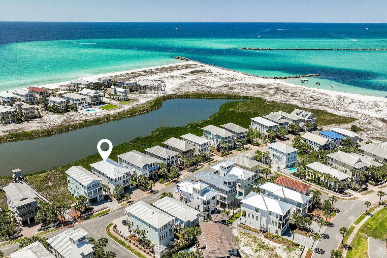 Exceptional views and attention to detail define this coastal modern retreat. Overlooking coastal the coastal dune lake, Lake Christina, this home affords extraordinary views of the lake, Destin's East Pass and the Gulf of Mexico. It's well appointed and has been meticulously thought out from design to conception with its two gulf side master suites, two guest suites and additional bunkrooom with four berths which make this home an ideal retreat for large families. In total there are five and a half baths; giving each bedroom including the bunks, their own bath. Interior finishes are impressive with notable features such as tongue & groove ship lap siding, vaulted beamed ceilings, private elevator; along with wood and tile floors throughout. The first floor.....