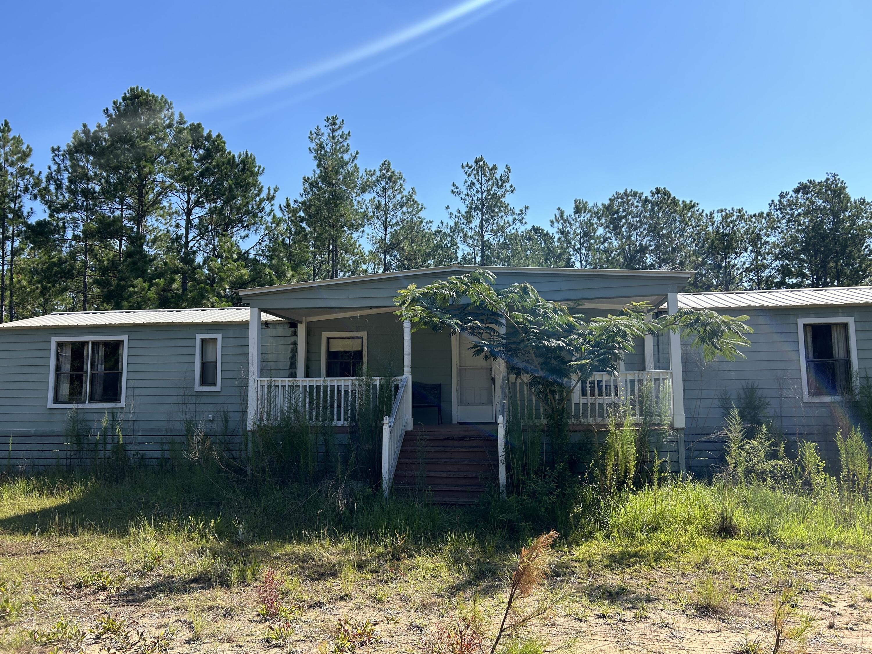 Affordable mobile home located on outskirts of Ponce de leon in Holmes county. This mobile home could be brought back to life with some elbow grease. It has good bones including original exterior walls being replaced with Hardi Board, both bathrooms have been tiled, floors are solid. Split bedroom plan both having walk in closets. Large covered porches on front and back. Back porch screened. Metal 2 car carport plus two other exterior buildings. Well water and septic. Stainless steel fridge and stove, stackable washer/dryer. HVAC is 7 ton.