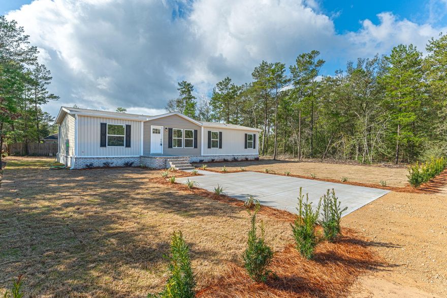 Welcome home to this stunning and brand new 4-bedroom, 2-bathroom manufactured home on a spacious 1/4-acre lot! Nestled on a peaceful county-maintained road, this residence offers the perfect blend of modern living and serene surroundings. As you approach, notice the attention to detail with the brick skirting and well-manicured yard, providing an immediate sense of curb appeal. The entrance is highlighted by a large concrete parking pad for two cars, complemented by a concrete walkway and a front porch adorned with a mix of concrete and brick - the ideal spot for enjoying the tranquil surroundings. Step inside to discover a thoughtfully designed interior that boasts an inviting atmosphere. The heart of the home is the kitchen, featuring a striking kitchen island illuminated by recessed lighting and cabinets galore. The perfect setup for entertaining or enjoying family meals, this space seamlessly flows into a large dining area. The coffee bar adds a touch of luxury, providing a cozy spot to start your day or unwind in the evenings. The laundry room adds convenience, making household tasks a breeze. There is a split-bedroom layout with the master suite on one side and the additional bedrooms on the other. The master bathroom is complete with a double vanity, a walk-in shower, and a generously sized walk-in closet. Throughout the home, enjoy the timeless elegance with upgrades including porcelain sinks in the bathrooms and a deep stainless-steel sink added in the kitchen. The comfort provided by the upgraded 5-ton HVAC unit is a bonus and a blessing with its energy efficiency. The home throughout has Lux Low E Thermo-Pane windows that fold down for easy cleaning & maintenance. Step outside to the back porch, where a deck awaits, creating an ideal space for outdoor gatherings or simply enjoying the fresh air. The partial privacy fence gives a sense of security & seclusion to the backyard and the perfect spot for a barbeque grill. Seamless rain gutters have been added all the way across the front and back of the home. Situated just approximately a 10-minute drive from town, this home offers the perfect balance between rural tranquility and urban convenience. With public water and underground power, this residence is not only aesthetically pleasing but also equipped with modern amenities. Don't miss the opportunity to make this beautiful home yours - Your new home awaits you!