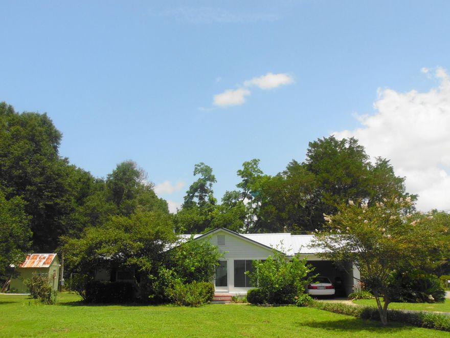 Cutest EVER country home on 1 acre, near town, perfect for a couple or small family. Has a front and rear carport that could possibly be enclosed to add more living area if needed. Glassed in Florida room on the front that is perfect for those who love house plants and flowers. Has window a/c, city water and septic. Also has a camper setup- power pole, septic and water hookup. Beautiful lawn and shrubs and bordering plants with grape vines and pecan trees in the backyard.