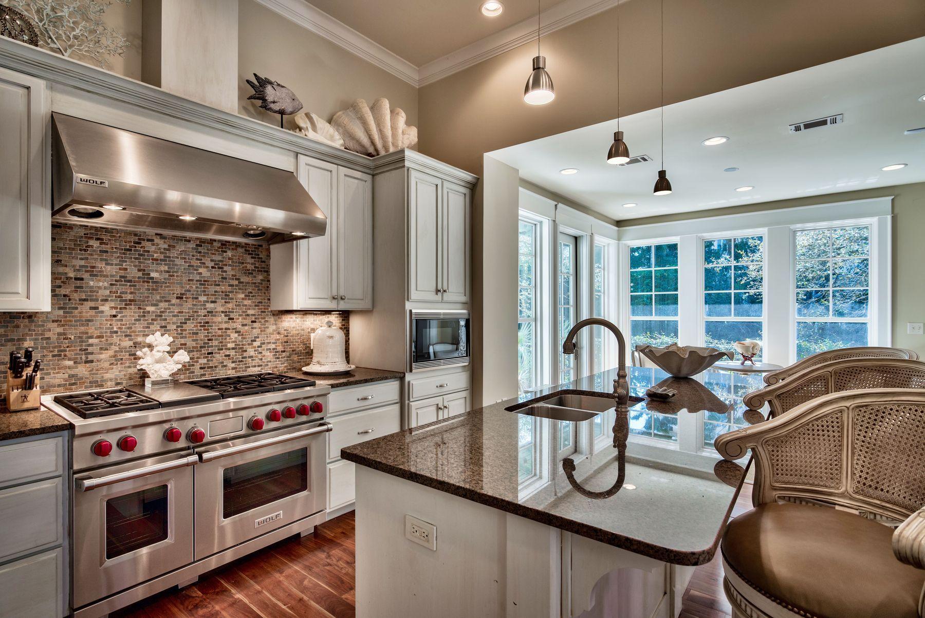 Luxury Living in an Architecturally Significant Waterfront Home. In an exclusive, waterfront enclave, this interesting home embraces outstanding architecture, fine workmanship and grand style. The West Indies style exterior offers little to prepare you for the exquisitely crafted and majestically furnished interior. A unique blend of Old World and New Florida offers a premium lifestyle for entertaining and stellar golf and beach amenities. The foyer soars to a second story with a beautiful, curved staircase. Expansive living spaces are flooded with natural daylight, and a casual sunroom sports multiple French doors to a slate patio on the waterfront and a private pool. The Wolf range has double ovens and range tops, and stainless steel appliances are at home among granite countertops and