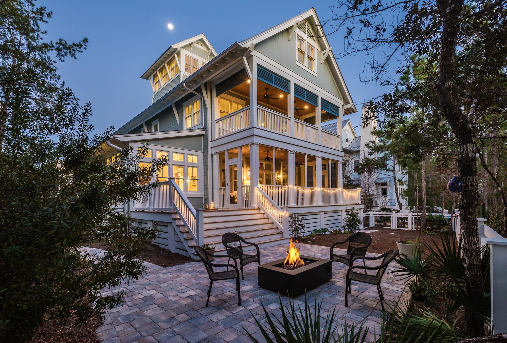 This four-story lakefront home greets you with the glow of gas lanterns, a spacious covered front porch with stately blue board and batten shutters and an accentuated shiplap ceiling that adds warmth to the space. This WaterColor home offers a coveted main floor master suite and a bonus bunk room with fun and functional living space on each level. A cozy seating area arranged for conversations and a front porch swing create the perfect place to unwind after a day at the beach. Large windows with transoms flood the welcoming foyer wrapped in shiplap with natural light. The soaring ceilings pull the eye upwards and an exposed brick accent wall draws you into the space. The warm walnut floors lead you to the heart of this 4,433 square foot home, where you will find an expansive