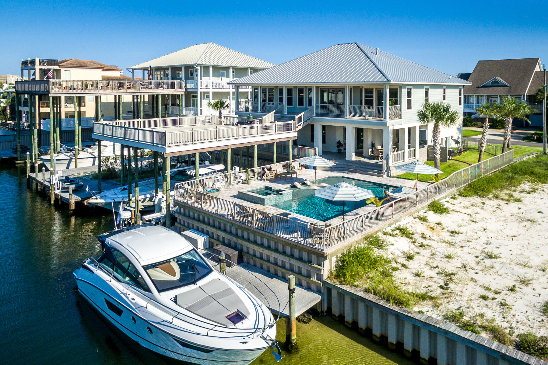 Amazing waterfront living! This stunning home offers a fabulous lifestyle inside and out! Located on a protected canal one lane back from Destin Harbor, two covered slips will accommodate boats up to 52 feet long, plus the dock configuration offers a 45-foot layup dock, a 30-foot layup dock, a 10,000 lb. boat lift, and a jet ski lift! You'll continue to enjoy the outdoors at the gorgeous brand-new pool, hot tub and patio, or on the massive open deck for sun soaking (or star gazing). There are also covered, shaded deck spaces on both levels, which expand the livable space considerably.The foundation of the 2-story home, which was built on raised ground to be above the flood zone, consists of forty 18'' pilings drilled 30 feet into the ground and covered with concrete slab,