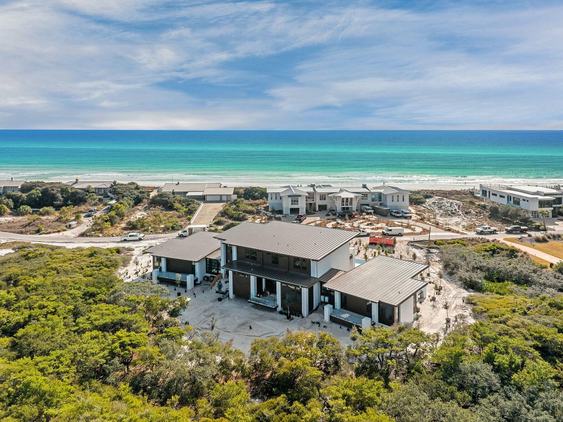 Coastal enchantment unites with progressive modern luxury at this bespoke new construction offering in the untampered community of Four Mile Village. Surrounded by the protected Coffeen Nature Preserve to the north and the Gulf of Mexico to the south, the serene neighborhood provides an idyllic locale for this prominent showcase home, situated on an elevated one-plus-acre parcel, one row off the gulf. Designed to be equally whimsical and bold, the progressive design bridged elements of mid-century design principles and married them with features designed to enhance contemporary beach living. Architect Gregory D. Jazayeri masterfully used the topographical elements of the raised parcel to incorporate view corridors, stacked building elements and elongated outdoor living spaces rarely found in typical coastal builds. Centralized around an open-concept living/dining/culinary space, the home functions surrounding two main wings, offering flanking primary bedrooms on both the west and east of the home. Each primary wing provides unfaltering luxury and crisp clean design, thanks to interior finishes and fixture selections by world-renowned Kenneth Brown Designs. Thick-cut marble, heavy brass and crystalline glass are showcased throughout the primary ensuites, while the curated culinary space provides unbridled views overlooking the Gulf of Mexico. The second level of the home showcases three additional private bedrooms, each with ensuites, as well as an expansive entertainment area equipped with a wet bar and additional full ensuite for the ultimate in flexible spaces. Located directly beneath the eastern primary wing of the home, an oversized two-car garage provides unparalleled security and privacy, while natural vegetation crafts enchanting outdoor spaces to the north and south. A private pool with sunning deck and infinity edge provides an exceptional relaxation and entertainment space overlooking both the Gulf of Mexico and the community, offering vistas to both the east and west. This property is currently under construction and expected to be complete by early Spring 2025. Digital renderings of the interior furnishings and finishes are representations of what the property may look like upon completion. 