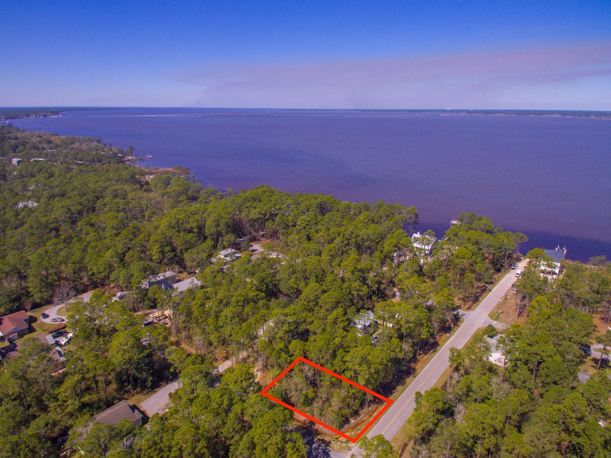 Beautiful wooded corner lot with bay view potential! Lot is in the preferable Flood Zone X (No flood insurance required) This quiet neighborhood offers seclusion and close proximity to the bustling 30A. The lot has great flexibility as it can be accessed from either Cabbage Rose or Summer Breeze. It features County paved roads, no HOA fees, and a boat launch at the end of the street contribute to the desirability of this lot plus it is less than an hour drive to the international airport in Panama City.