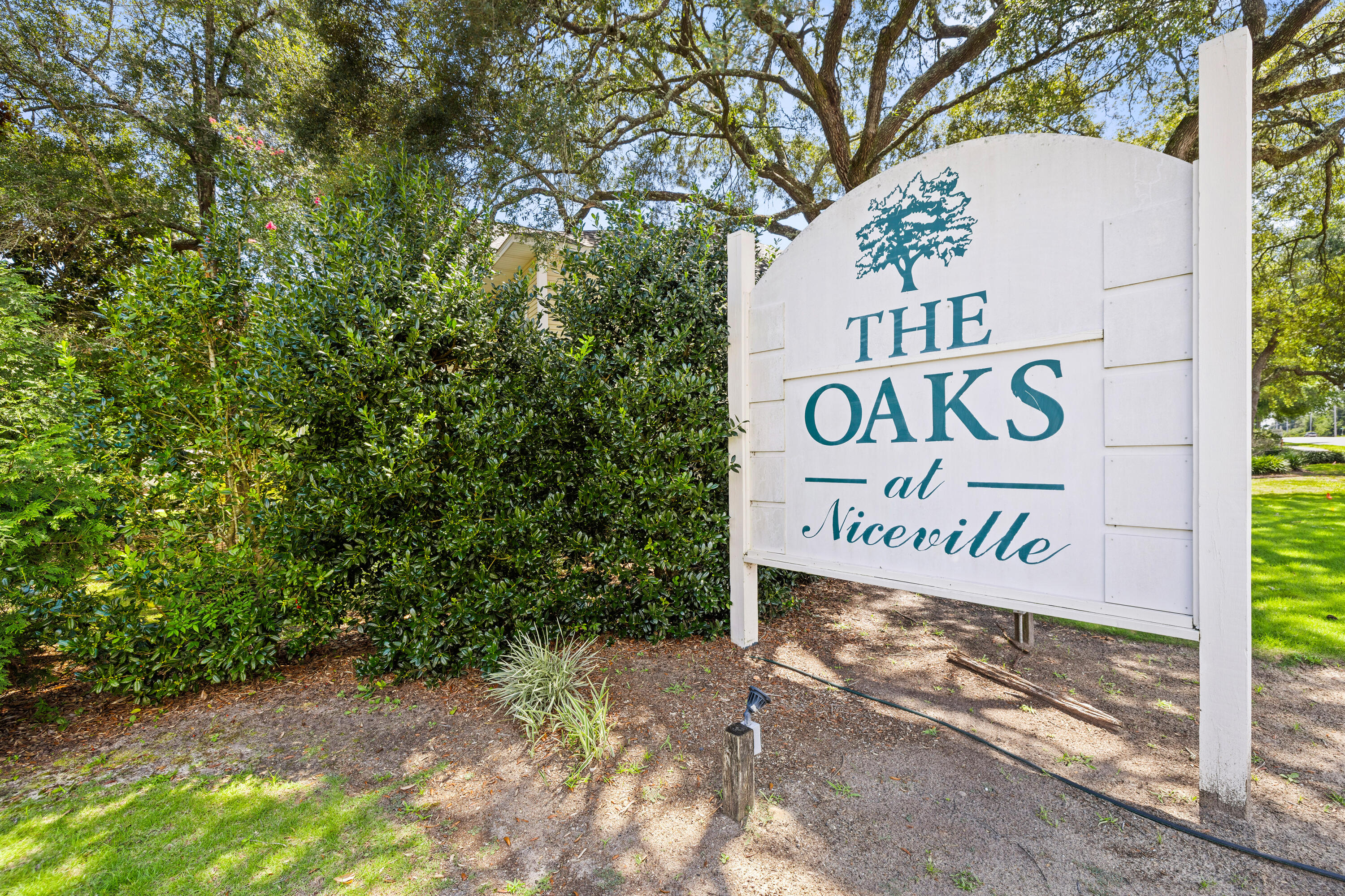 A charming furnished first-floor oasis is waiting for you to discover the low-maintenance and well-maintained unit tucked at the rear of building #13. Imagine stepping off your private porch while the summer breeze rustles through mature Leland Cypress needles. As you cross the threshold of the front door, the 9-foot ceilings and soft planks of new vinyl flooring welcome you home. Sunlight filters past neutral-hued walls and faux blinds, casting a gentle glow on the sleek white kitchen where the aroma of fresh coffee drifts from a cup perched beside the glass-top stove. In the mornings, you can linger over breakfast in the dining area. Late afternoons are spent lounging poolside with neighbors you've come to know by name. Evenings are spent relaxing in the living room, (click 'more') where there is a dedicated alcove designed for your big-screen TV. Nights find you curled up in your master haven, doors closed against the world, surrounded by garments curated in your walk-in closet. This isn't just a condo - it's where your next chapter in life begins. Both bedrooms boast ceiling fans, faux blinds, and window sheers, 6-panel interior doors. The master offers a walk-in closet with extra hanging poles perfect for the fashion-forward homeowner. The guest room has added shelving for storage or additional organization. The hallway features a utility closet and the laundry closet that is equipped with a stackable washer and dryer, making laundry day a breeze. The Oaks community amenities include an in-ground swimming pool, multiple gazebos, bicycle racks, BBQ grills, and lush landscaping. Everything you need is included - just bring your suitcase and settle in. Oh, did I mention that the middle school, high school, children's park, library, and more are located within just a few short minutes of this community?