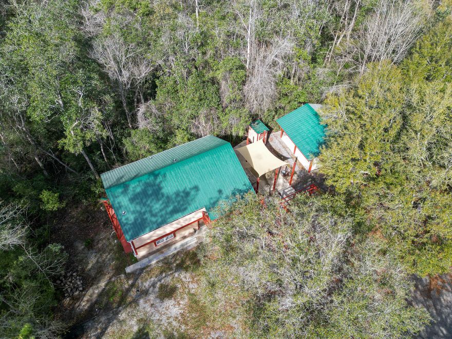 LIVE YOUR PEACEFUL LIFE RIGHT HERE!!  This home is surrounded by 12 Acres of land, the front part is cleared for the homesite, just behind the home is the spring fed stream, Joyce Branch, that runs through the property, beyond that is the enchanted forest with horse/4-wheeler trails.  The home has been updated with a new roof, new HVAC, granite countertops, and the garage has been tastefully converted to a bedroom with a full bath, it is perfect for your guest.  There is a modern day ''outhouse'' with real plumbing, 2 horse stalls and a tack room or use the stalls for 4-wheeler parking. There's more...a parking slab with utility hook-up (power, water, sewer) for your RV or your RV traveling guest.  POSSIBLE OWNER FINANCING WITH 50% DOWN.