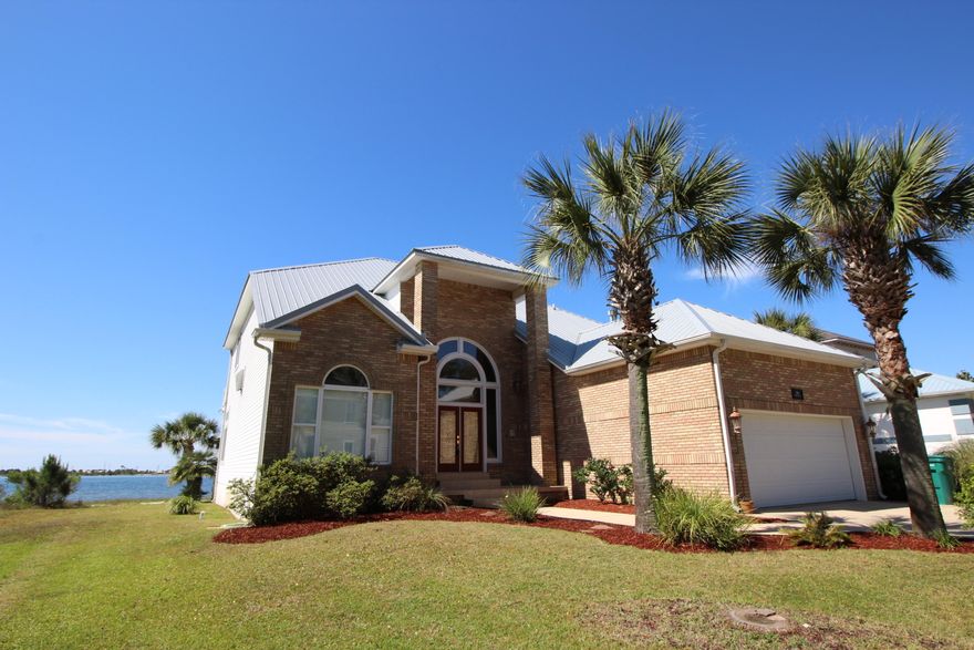 COASTAL LIVING AT ITS FINEST! Beautiful entry with custom arched window and leaded glass doors that lead into the foyer with high volume ceilings and an open staircase to the upstairs. Formal elegant dining room has a trey ceiling with accent lighting, chair railing and wainscoting. Spacious living area with crown molding, recessed lighting, corner fireplace with custom mantle and tiled front and French doors that welcome you to the veranda with incredible water views. Gourmet kitchen with chic knotty pine tongue and groove ceiling, recessed lighting, custom cabinets with glass fronts and lighting, beautiful granite counter tops, upgraded appliances to include a Wolf gas stove with built-in grill and a center island with veggie sink. Breakfast area is surrounded by windows overlooking