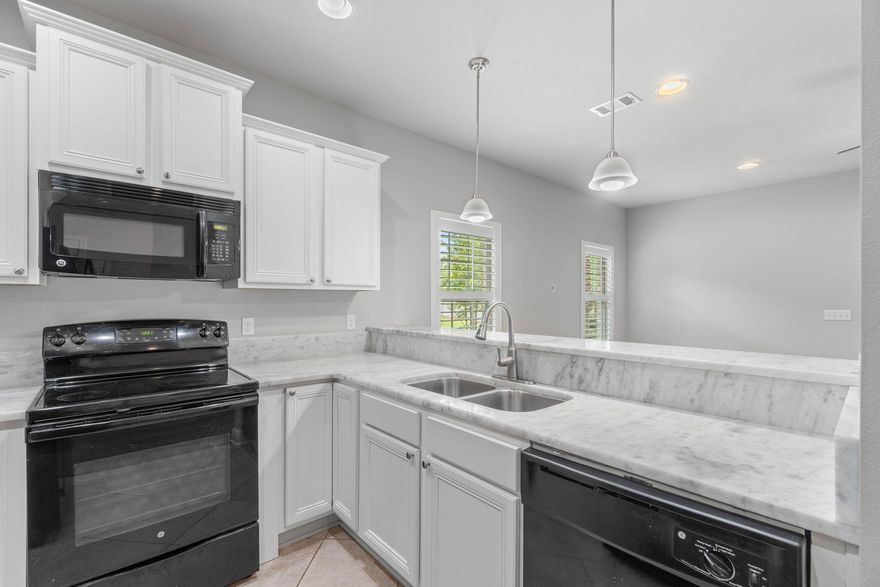 Simply Said....Welcome Home If you're looking for that move in ready home~look no further ...this wonderful Town Home End Unit offers an ideal location in a small community sub-division, Located in EAST NAVARRE Your 3 bed/ 2 1/2 bath home offers great family living space~just minutes from the beach~local stores and within easy driving distance to Hurlburt Field AFB. Community offers great curb appeal, with sidewalks~Community Pool & Playground~Landscaping & Palm Trees. This home is ideally situated in the center of the community with common green area to the side ,beautifully landscaped and fully enclosed back patio area. Entering the home you will be greeted by a entrance foyer with open flow to the great family room/dining area with gorgeous wood plank flooring & plantation shutters making the living space cozy and bright. French door leads out to the back-garden courtyard which is fully fenced for privacy and enjoys a custom built gazebo ,palm trees and has graveled borders for low maintenance.
Wonderful kitchen with white staggered cabinets~ under cabinet lighting, hop up breakfast bar and black Appliances. Downstairs also has a ?? bath with granite & under mount sink .Large Master bedroom offers a walk-in closet with custom built shelving & drawers. Master bath has a granite double vanity & this unit is the only one with an oversized step in shower. Additional bedrooms are a good size with large closets and additional bathroom with granite vanity ~ tub/shower. Laundry closet is upstairs for convenience. Home owner has installed~ LVP flooring ,Plantation shutters & blinds throughout~ceiling fans and a front storm door. HOA includes exterior building insurance and grounds maintenance. Call today to make an appointment to view this wonderful move in ready home.