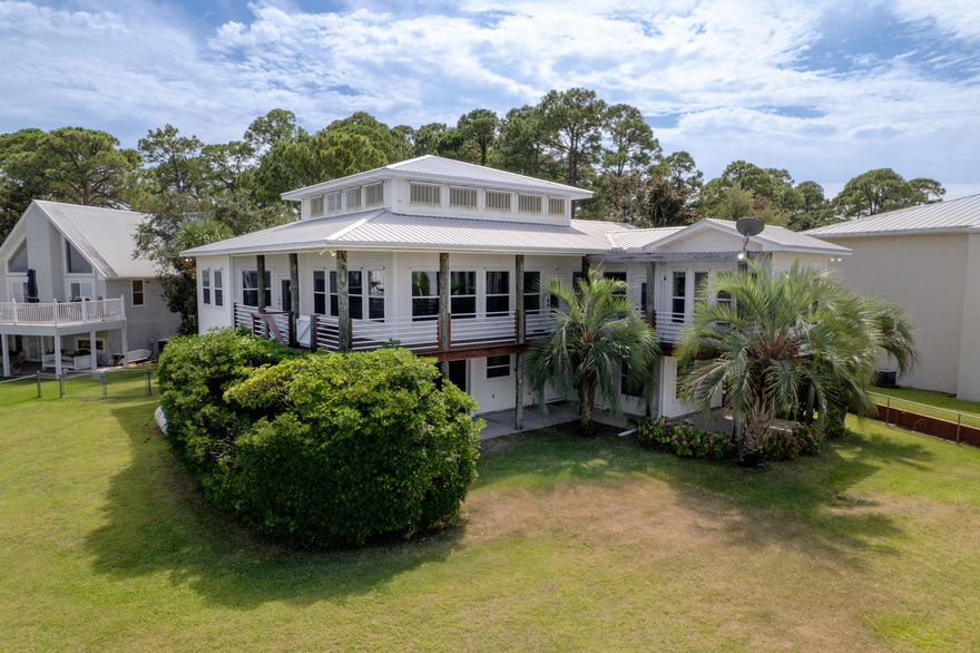Live the dream in this spectacular Bay front oasis thoughtfully positioned on a rare double lot, where dazzling sunrises and sunsets light up the sky as dolphins glide past. Wraparound porches and patios offer breezy, shaded spaces to relax or entertain in true coastal style. The sun-filled main level features an open great room with panoramic views and access to a covered deck. An elevator makes daily living effortless. Private lower-level suite boasts a full kitchen/bath, spacious bedroom, and private patio--perfect for guests or extended family. A deep two-car garage with rear door offers ample storage for kayaks, paddle boards, or golf cart, plus workshop space. This home also has an emergency generator. Private dock features two boat lifts, including a covered lift with remote, a walkaround dock, and a fish cleaning station for the catch of the day. Paradise awaits!"