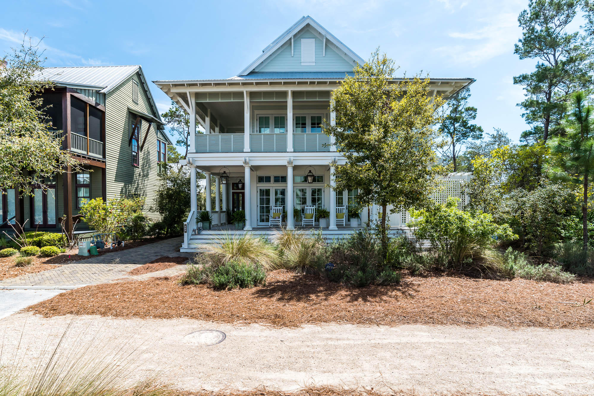 If you have an affinity for the Florida outdoors, you will fall head over heels for this four-story WaterColor Lakefront home with a two car garage and appointed carriage house. This home professionally decorated by Urban Grace Interiors is a MUST SEE! Brick paver pathways transport you to the perfect people watching perch in WaterColor; the homes expansive, wrap around front porch with stately white columns, inviting wood rockers and the glow of the gas lanterns warmly welcome you home. As you enter the home's French front door, you are greeted with white shiplap walls, soaring soft-blue shiplap ceilings, and natural light abound. The open floor plan great room features 7 sets of French doors with transom lighting leading out to the covered porch, a large dining room