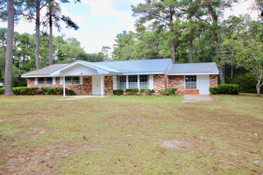 #LetsGoRetro! Rare opportunity to own a well maintained Chicago brick ranch style home on 2.54 lushly landscaped acres (technically in the county, but ''in town'' just1/4 mi from Walmart and could possibly be annexed into the city). NEW metal roof. New exterior trim paint. 4 beds/3 full baths. The master bdrm could be used as a home office or college student's room with separate entrance. Sunroom and large family room with huge Chicago brick fireplace. Outside you'll find a brick storage shed, a much larger storage shed, mature trees & huge azaleas. Plum, pear, persimmon, satsuma & scuppernong grapevines. Rarely do you find acreage in this location. As part of an estate, being sold As Is.