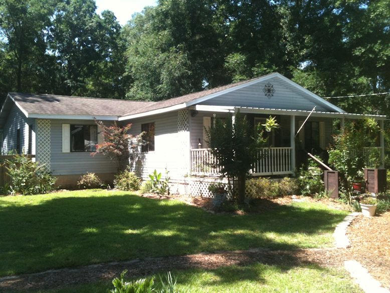 Owner in the process of moving so house is available now. Bring all offer. Beautiful low maintenance affordable home on a large acre wooded lot gives you lots of privacy. Large county front porch is perfect for sitting in those rocking chairs and enjoying a relaxing evening. Original home built in 1991 is off grade with master bedroom and Florida room added in 2009 on slab. Home was completed gutted and remodeled in 2009 with new bathrooms, new kitchen, new appliance, new HVAC, new roof, etc. Custom kitchen cabinetry with laminate counter tops. Heated and cooled Florida room off the kitchen gives that extra space for kids room, man cave, study or whatever your needs are. Small room has been added off the back for extra storage space. Refrig., washer, dryer do not convey.