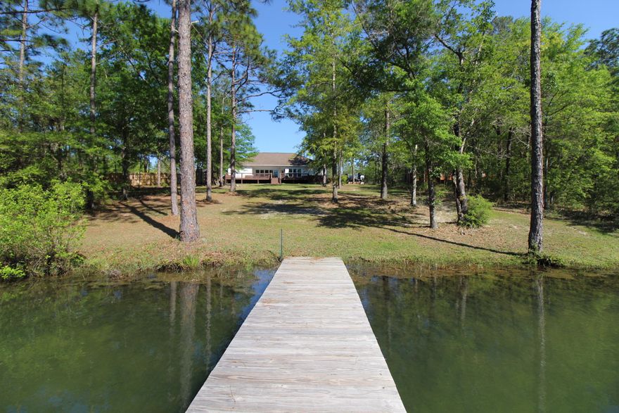 Are you searching for 'Tranquility' then this Lake Front home is the one! Your search is over.  This home is nestled on a spring fed lake in northeast Crestview on 1.20 acres. Lakefront at affordable price. As you approach this Lakefront home, you will be welcomed by the calming sounds of nature and birds chirping. Covered front porch leads you into the home with sights of the lake through the wall of windows across the back wall. Look up and admire the double trey ceiling and farmhouse rustic featured light. New LVP flooring through main living areas, newly painted in today's modern colors. To your right is a bedroom or office with built in cabinet and countertop and new carpet. To your left is the formal dining room with another double trey ceiling. Straight ahead is the large family...