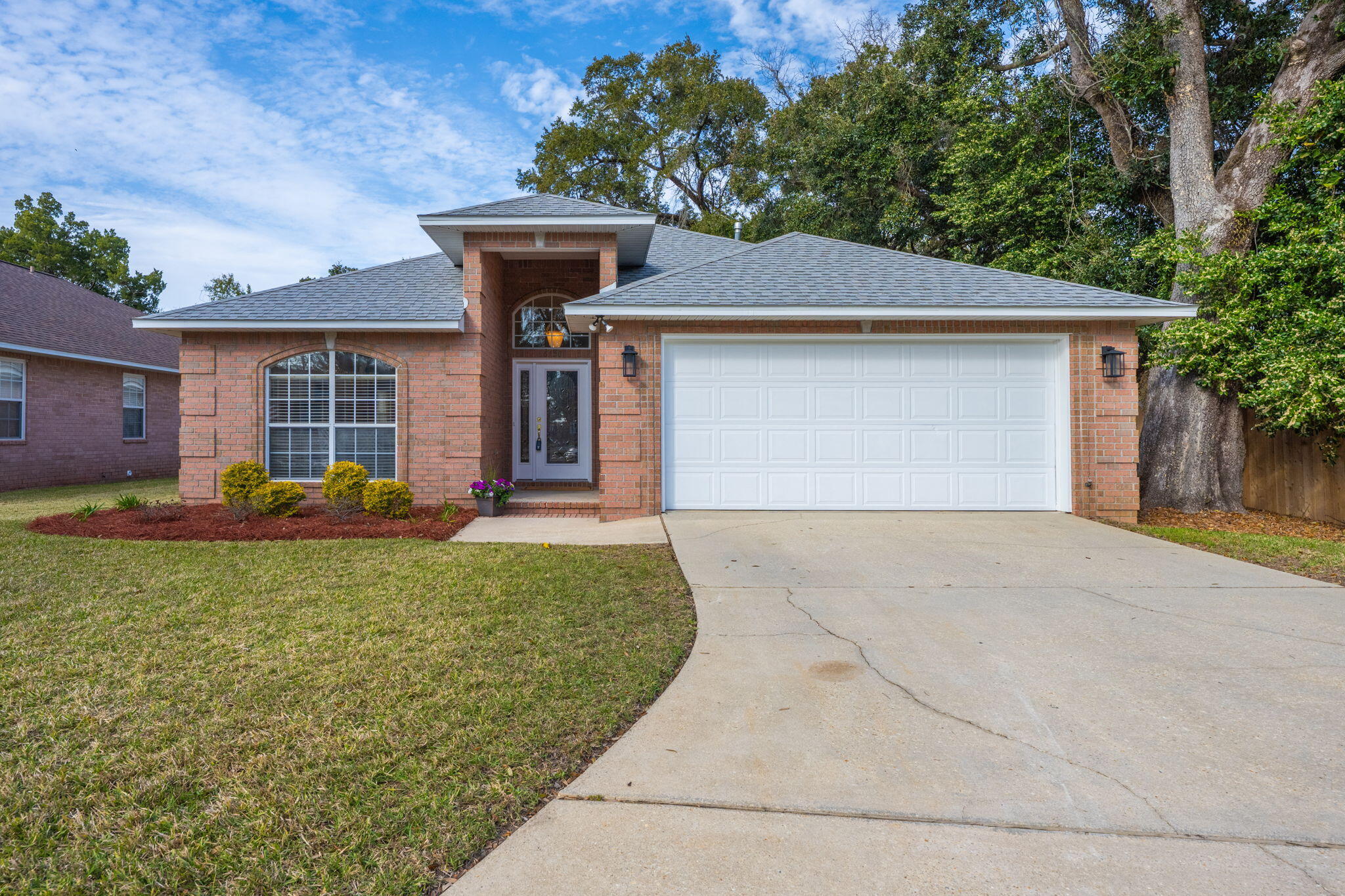 Discover this well-maintained brick home, nestled at the end of a quiet cul-de-sac and backed up to a green belt that will never be developed! Located in a friendly neighborhood off Scenic Highway, this home features 3 bedrooms and 2 bathrooms, an open-concept layout, fresh interior paint, and a brand-new roof installed in 2022. Step inside to find tile flooring throughout the main living spaces, with plush carpet adding warmth to the bedrooms and living room. The spacious kitchen boasts granite countertops, ample cabinet space, a built-in microwave, an eat-in area, and a breakfast bar. The inviting living room features a vaulted ceiling, built-in shelving, and a cozy gas fireplace with an elegant mantle, making it the perfect gathering space. The private primary suite is a true retreat,  featuring a large walk-in closet and an en-suite bathroom complete with a double vanity, jetted soaking tub, separate standing shower, linen closet, and water closet. A tray ceiling and a large double window enhance the space, offering natural light and a lovely backyard view. The two additional bedrooms are tucked away in a private hallway, which can be closed off for added privacy. Each bedroom includes its own walk-in closet and shares a full bathroom with a tub/shower combination. The hallway also offers a coat closet and linen closet for extra storage. A bright and sunny Florida room with pocket doors leads to the backyard. The backyard, equipped with a privacy fence offers mature shade trees, a sprinkler system, and a spacious open patioperfect for relaxing or entertaining. Additional conveniences include a two-car garage that leads into a laundry room equipped with a utility sink and cabinetry. Located just one block from Gull Point Community Centerwith its fenced ballpark and playgroundthis home is also close to the University of West Florida, the airport, the hospital, shopping, and dining. Offering comfort and convenience in a prime location, this home is a must-see!