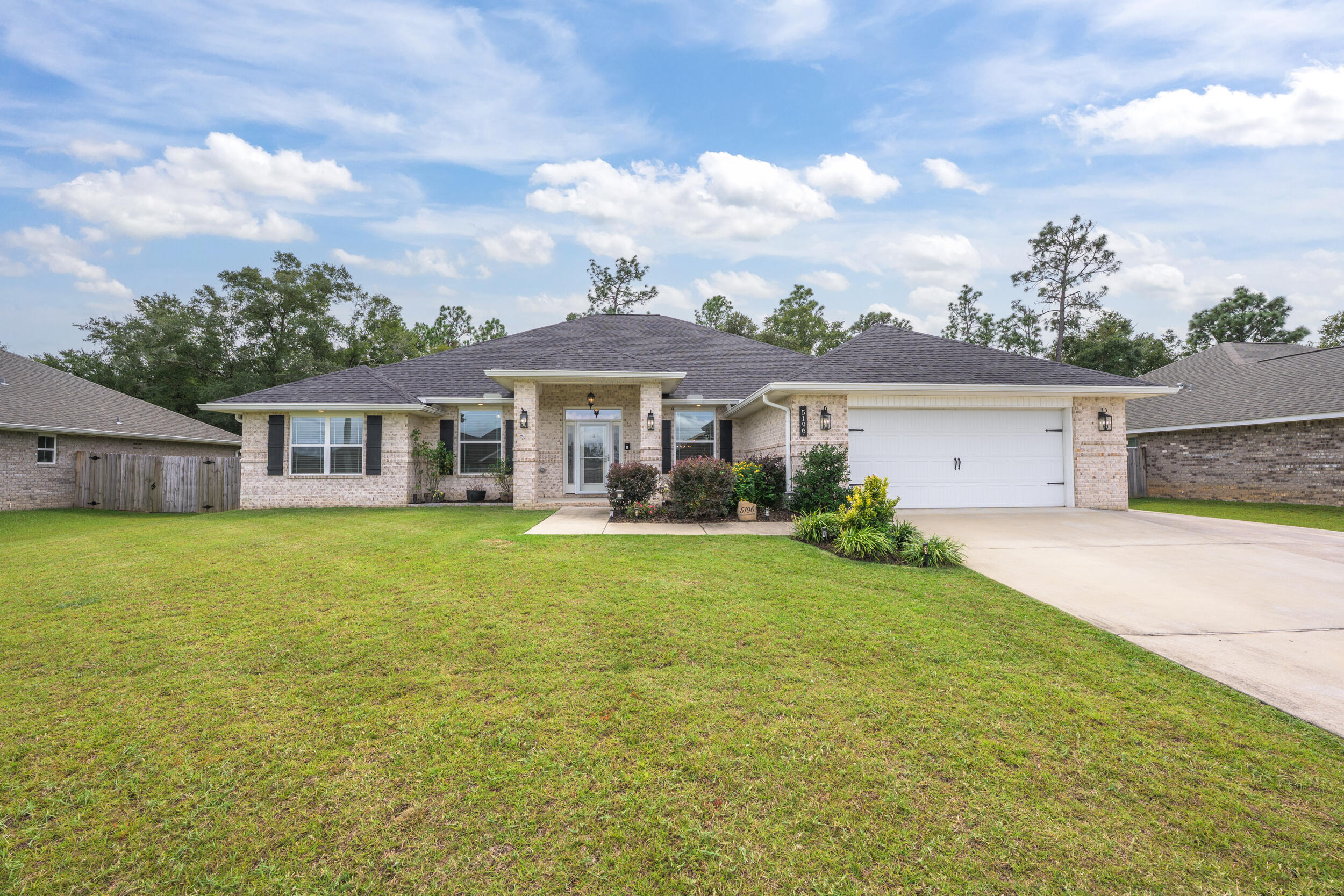 Welcome to this stunning 2021 brick home, thoughtfully crafted with elegant details throughout! Nestled in the well kept neighborhood of Plantation Woods, enjoy the freedom of no HOA along with an extended driveway, perfect for parking a boat or RV with ease. With a four-year-old roof, water heater, and HVAC, you can enjoy peace of mind knowing the major systems are up to date. Inside, neutral paint and LVP flooring create a seamless, inviting atmosphere across the open floor plan. The kitchen is a beauty, offering granite countertops, an island, a spacious pantry, and stainless steel appliances. Elegant tray ceilings and graceful archways add architectural charm, while the expansive 11x45 screened porch just off the living room extends your relaxation outdoors and offers the perfect p lace to unwind! The split primary suite features carpet, a tray ceiling and private screened in porch access. The en suite bathroom offers dual vanities, two expansive closets, a soaking tub, separate shower, and a water closet. For laundry made easy, there is direct access from one of the two closets to the laundry room. On the opposite side of the home, you'll find 2 hallways leading to two full bathrooms and three additional bedrooms, providing privacy for family members or guests. Each bedroom features carpet, a ceiling fan and ample closet space. The fifth bedroom is located just off the kitchen, offering versatile use to suit your lifestyle. With durable LVP flooring it's ideal as a bedroom, home office, gym, or even playroom. Outside, the peaceful backyard is enclosed with a privacy fence and surrounded by mature trees, creating a calming oasis. The property also includes an 11x11 shed for extra storage and a two-car garage with a workbench. This home is ideally located near the interstate for an easy commute and just 25 minutes from Navarre Beach and Pensacola. Move in ready and well cared for, this property is prepared to welcome its next family!