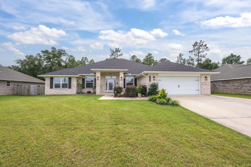 Welcome to this stunning 2021 brick home, thoughtfully crafted with elegant details throughout! Nestled in the well kept neighborhood of Plantation Woods, enjoy the freedom of no HOA along with an extended driveway, perfect for parking a boat or RV with ease. With a four-year-old roof, water heater, and HVAC, you can enjoy peace of mind knowing the major systems are up to date. Inside, neutral paint and LVP flooring create a seamless, inviting atmosphere across the open floor plan. The kitchen is a beauty, offering granite countertops, an island, a spacious pantry, and stainless steel appliances. Elegant tray ceilings and graceful archways add architectural charm, while the expansive 11x45 screened porch just off the living room extends your relaxation outdoors and offers the perfect p lace to unwind! The split primary suite features carpet, a tray ceiling and private screened in porch access. The en suite bathroom offers dual vanities, two expansive closets, a soaking tub, separate shower, and a water closet. For laundry made easy, there is direct access from one of the two closets to the laundry room. On the opposite side of the home, you'll find 2 hallways leading to two full bathrooms and three additional bedrooms, providing privacy for family members or guests. Each bedroom features carpet, a ceiling fan and ample closet space. The fifth bedroom is located just off the kitchen, offering versatile use to suit your lifestyle. With durable LVP flooring it's ideal as a bedroom, home office, gym, or even playroom. Outside, the peaceful backyard is enclosed with a privacy fence and surrounded by mature trees, creating a calming oasis. The property also includes an 11x11 shed for extra storage and a two-car garage with a workbench. This home is ideally located near the interstate for an easy commute and just 25 minutes from Navarre Beach and Pensacola. Move in ready and well cared for, this property is prepared to welcome its next family!