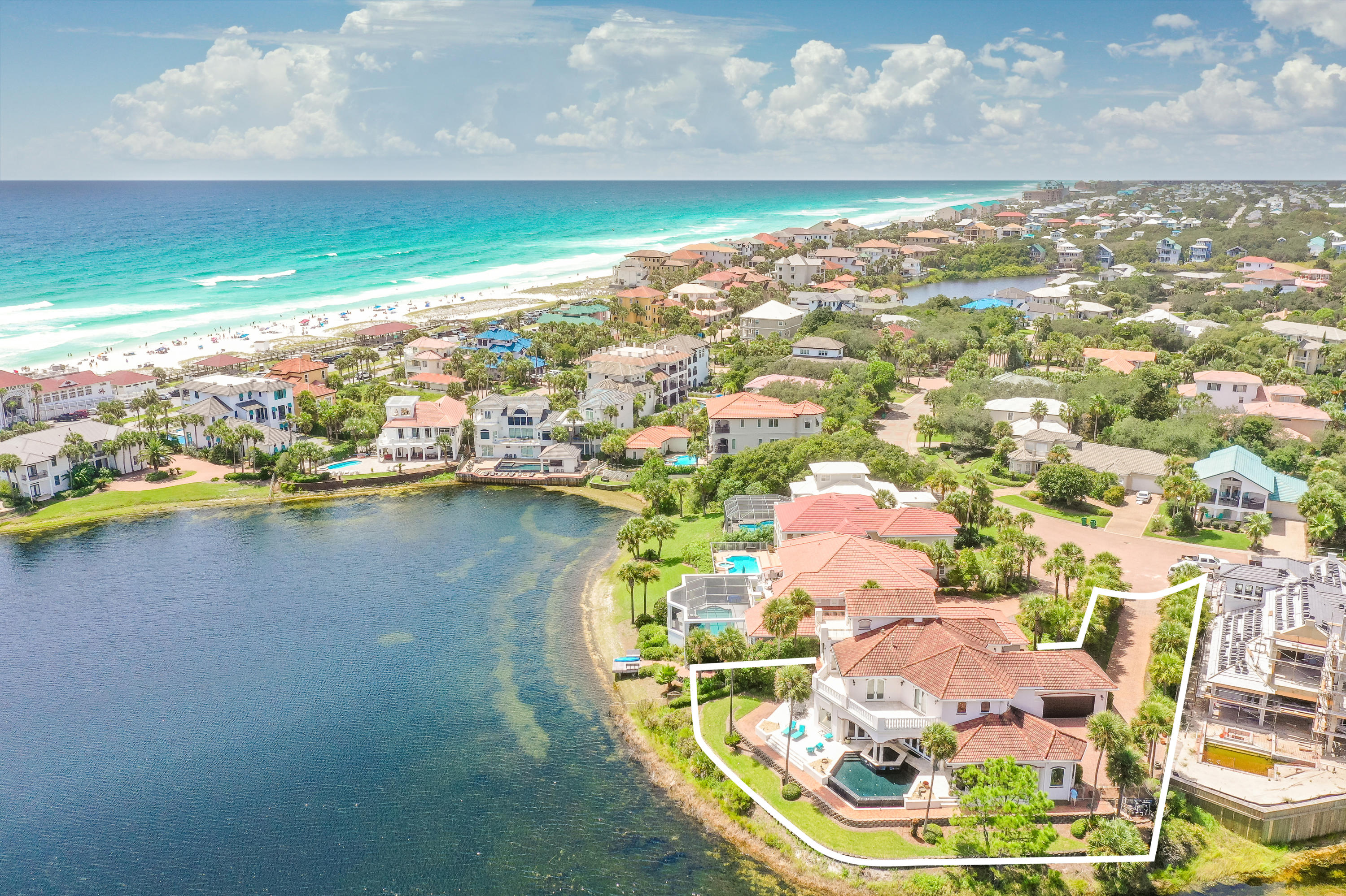 Prominently positioned with over 180' of premier lake frontage, this secluded beachside retreat is situated on one of the most coveted homesites in the esteemed gated neighborhood of Destiny. Sweeping gulf views and panoramic waterfront vistas abound from this sprawling four bedroom, four and a half bath mediterranean estate located just steps from the beach and offering a private gated driveway entry with resort style amenities. Characterized by classical mediterranean architecture and an exemplary open floorplan, this resort compound is highlighted by soaring double height cathedral ceilings, oversized first floor living spaces and an unparalleled outdoor pool deck overlooking Four Prong Lake.