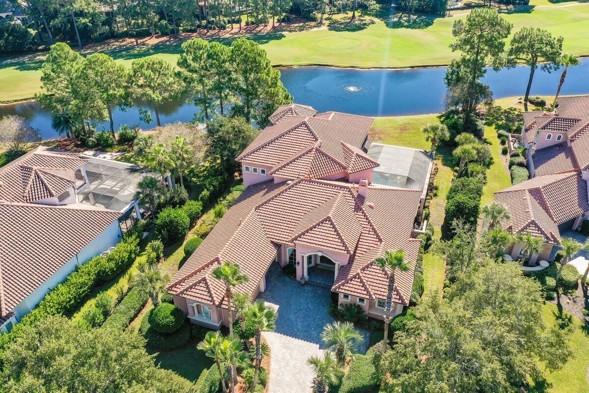 This palatial home in Burnt Pine delivers endless living space overlooking peaceful lake and golf course vistas. The private outlook enjoyed from the pool terrace, living areas, and master bedroom includes 117 feet of lake frontage. A paved driveway leads to a three-car garage. Step through the entrance door and appreciate the impressive sitting area with views of the lush outdoor living area and tropical landscaping. Cool tile floors, grand pillars and elaborate tray ceilings set the scene for a home designed for comfort and luxury. There's a handy granite-topped wet bar with drink refrigerator for serving perfectly chilled drinks to welcome guests. Views from the living area, breakfast nook and kitchen overlook the pool, providing seamless indoor-outdoor living with two fully retractable