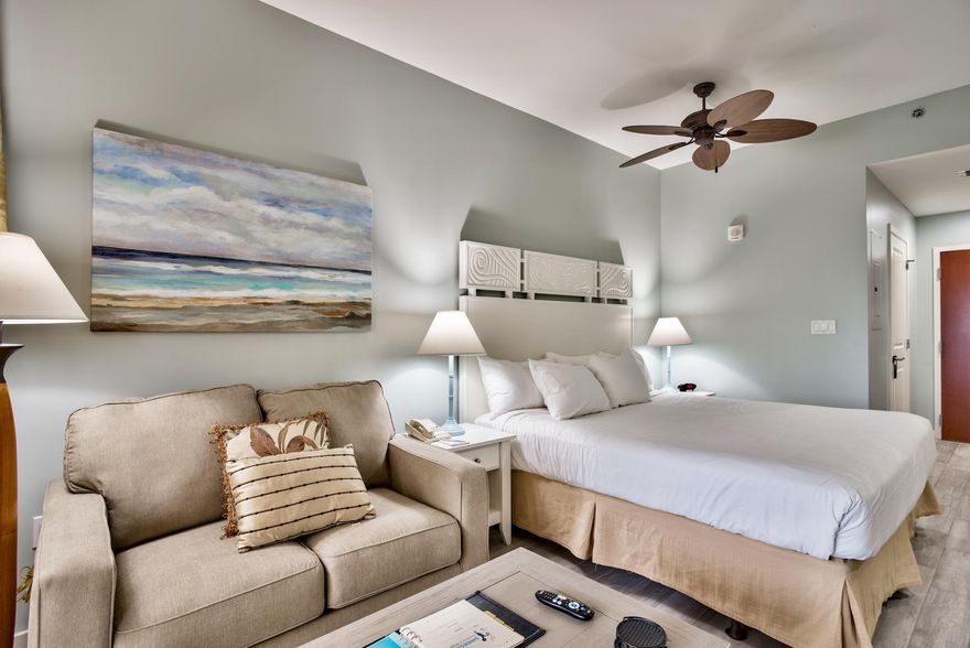 A rated studio on the Sandestin Rental program located on the 2nd floor in Luau looking south. Updated in the last 1-2 years, updates include Luxury Vinyl Tile (wood floor look), dinette, TV console with flat screen TV, and sleeper sofa. Luau offers a fitness center, a BBQ area, access to a lagoon style heated pool with side Tiki Bar (Tiki bar is seasonal), swim-under waterfall, hot tub, and easy access to the beach. Other amenities include covered parking and owner storage. In addition, owners can take advantage of the sundeck on the top floor with views of the resort.