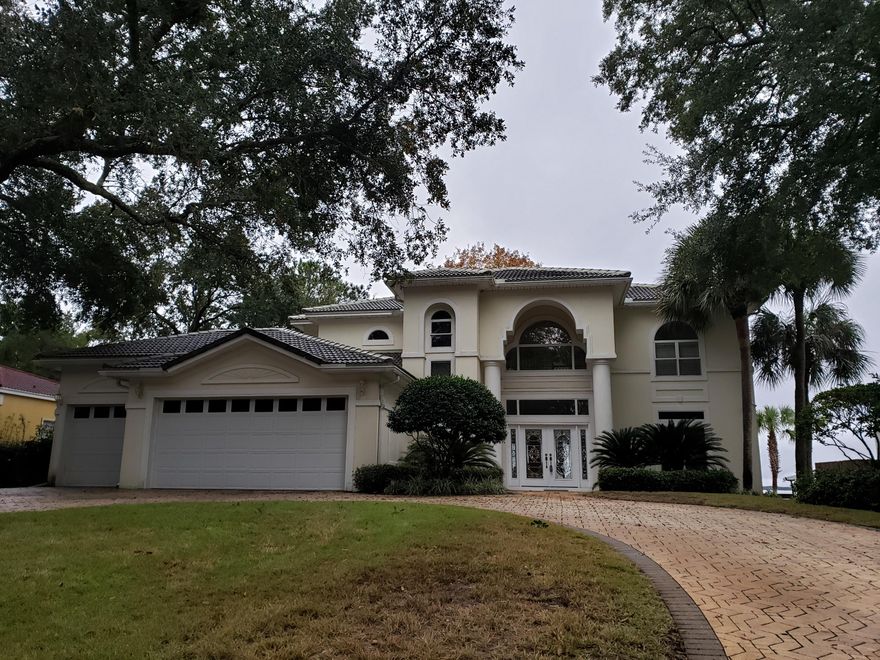 Don't miss your chance to land this fabulous home with 95 feet of bayfront living, a dock with power, water and a covered boat lift. The floorplan is to die for with two master suites that access outdoor spaces overlooking the bay, one on the main level and one upstairs. Two additional second floor bedrooms share a connected private bathroom with one having access to the balcony and a wall of windows overlooking the bay and the other with bay views. The kitchen is large with solid surface countertops, a center island and breakfast bar all looking out over that magnificent bay view. Soaring ceilings in the family room, built in surround sound system and french doors out to the back patio make this a room destined for friendly gatherings. Lets not forget the formal dining room and the